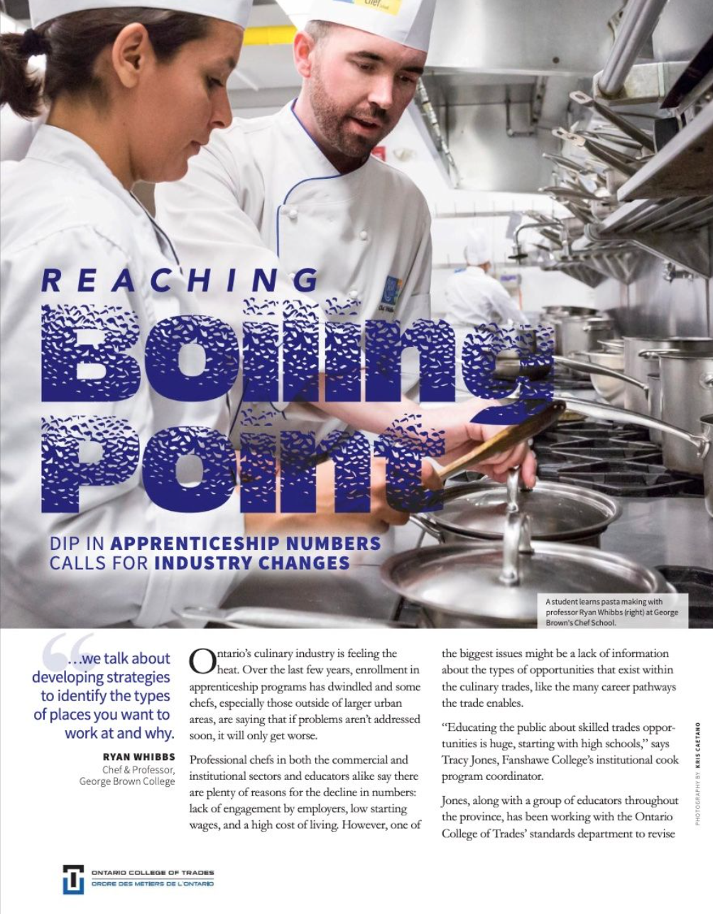 A student and teacher working in a professional kitchen with Dr. Ryan Whibbs, with the student wearing a chef's hat and apron, and the teacher guiding him with a tablet, surrounded by kitchen utensils and pots.