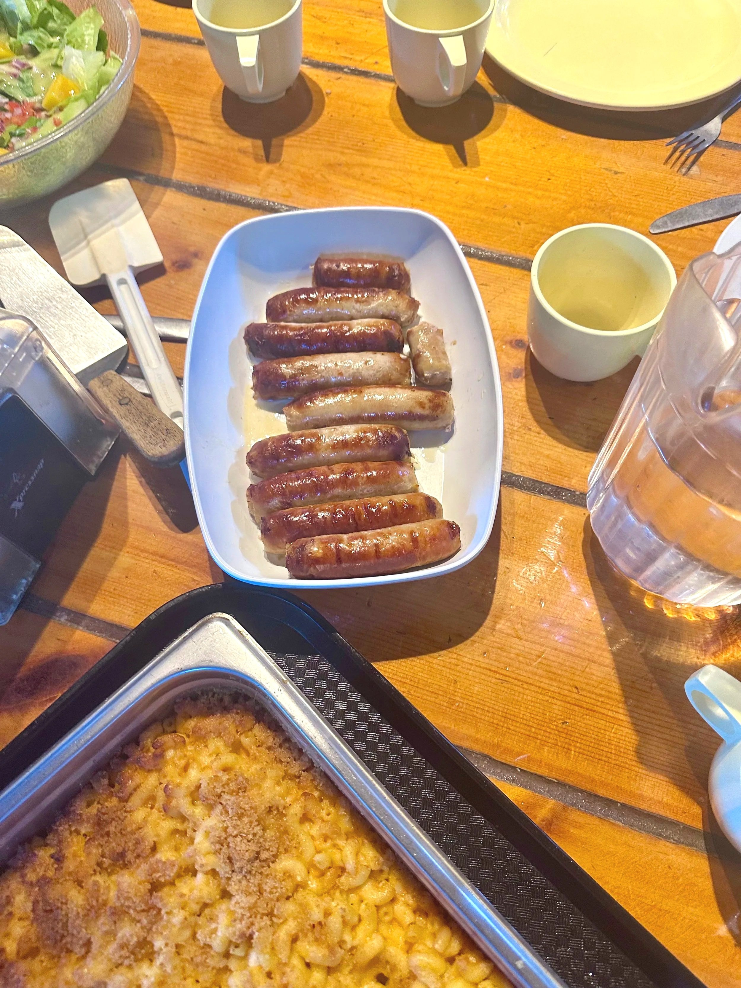 A tray of macaroni and cheese with a breadcrumb topping on a table set for a meal.