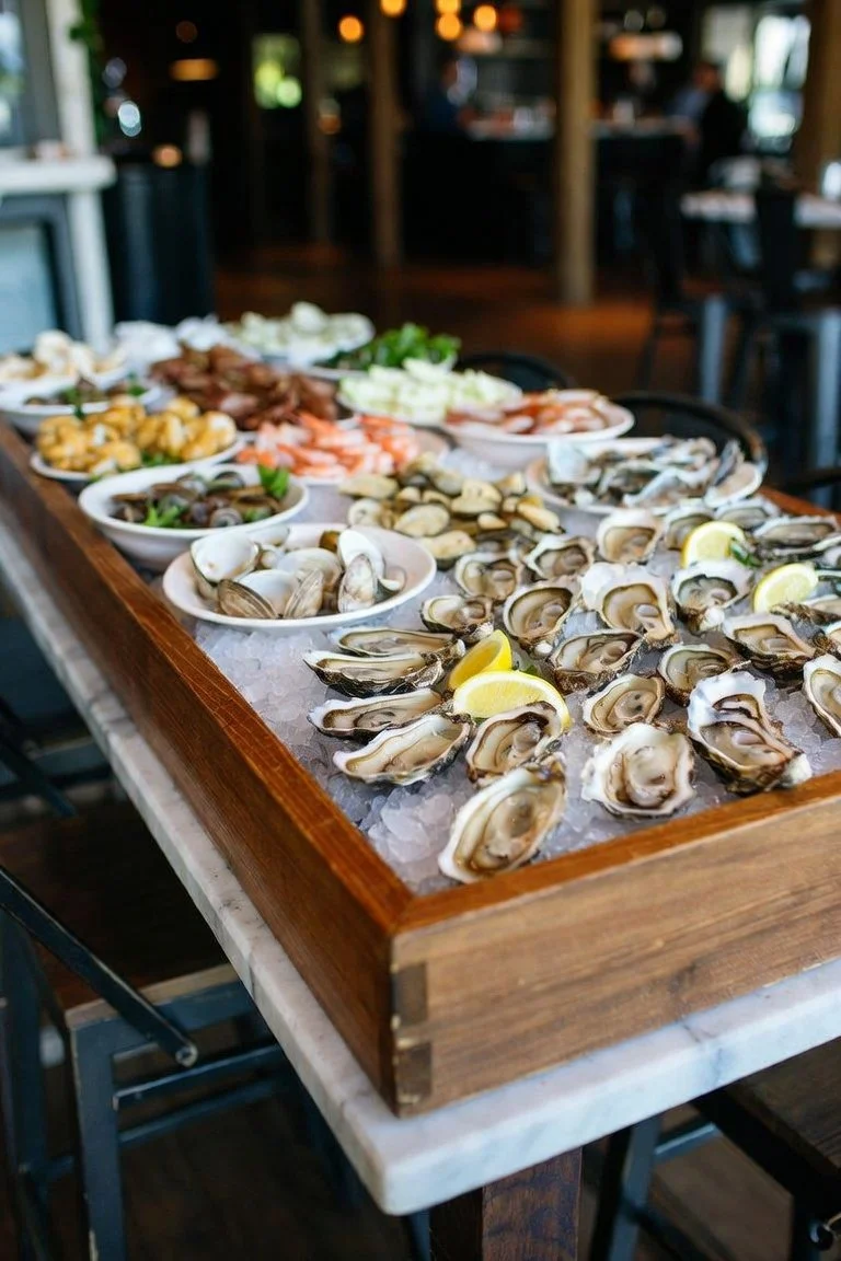 A wooden tray filled with fresh oysters on ice, garnished with lemon wedges at a seafood restaurant.