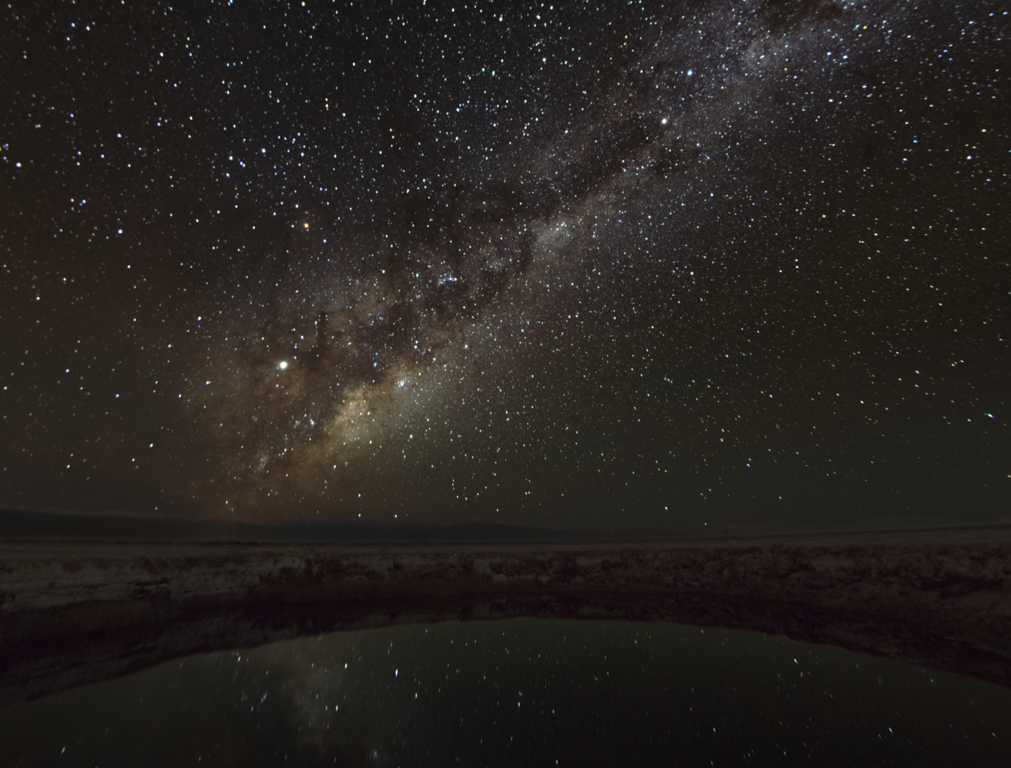 The center of the Milky Way Galaxy rises above the Chilean landscape, reflected in the still
waters of the Ojos de Salar in the Atacama Desert. | California Academy of Sciences