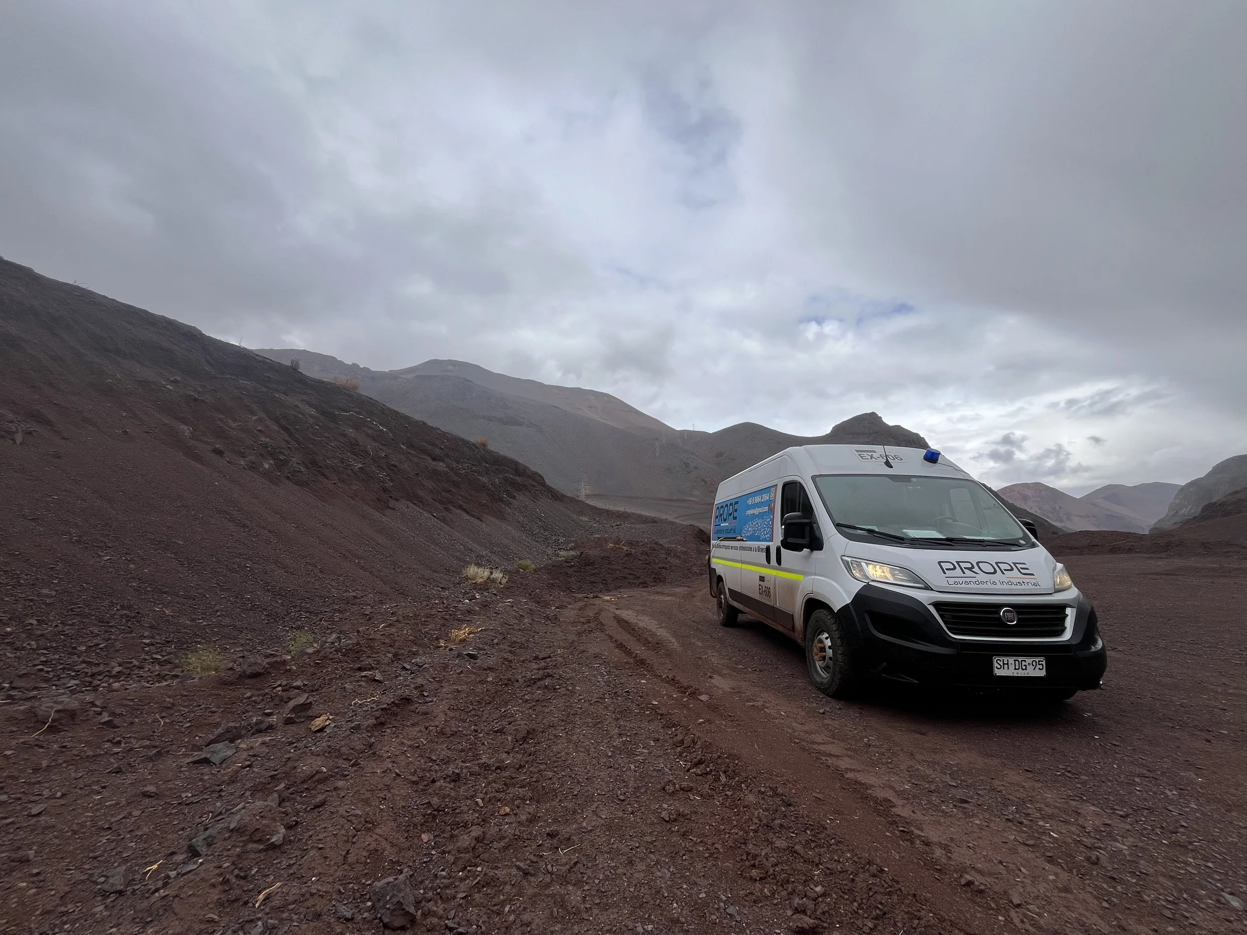 Camioneta blanca en un paisaje montañoso con cielo nublado.