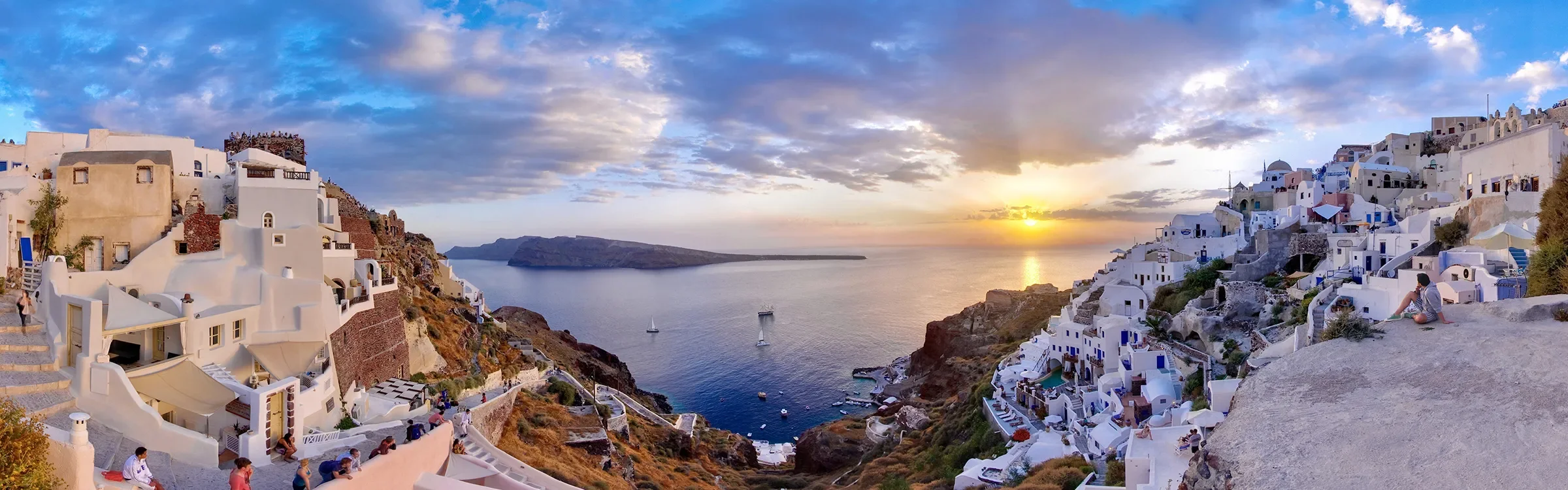 Panoramic sunset view of Oia in Santorini, Greece, representing ImmerseMe's immersive Greek language learning experiences inspired by authentic Greek culture and real-world locations.