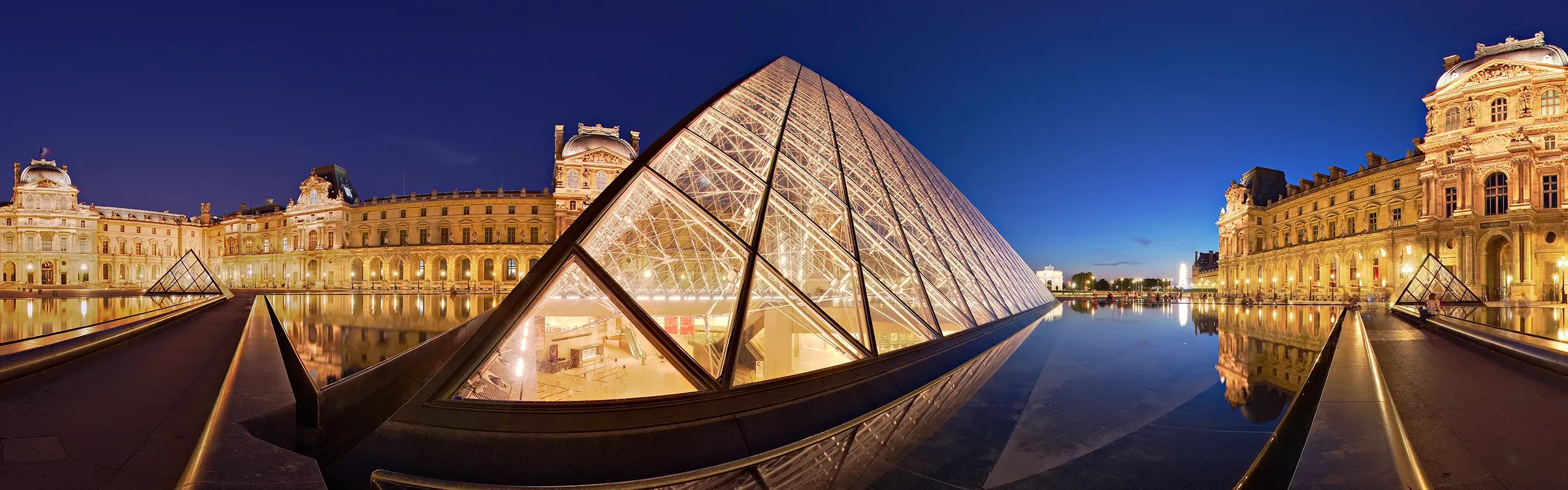 Panoramic evening view of the Louvre Museum in Paris, France, representing ImmerseMe's immersive French language learning experiences inspired by authentic French locations.