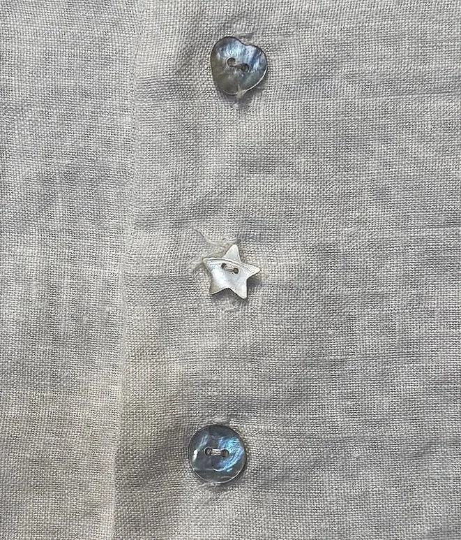 Mother of pearl star and shell button detailing on a women's button-down shirt.