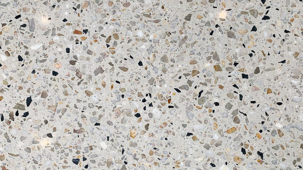 Close-up of a honed floor with small multicolored stone chips in a light cement matrix.