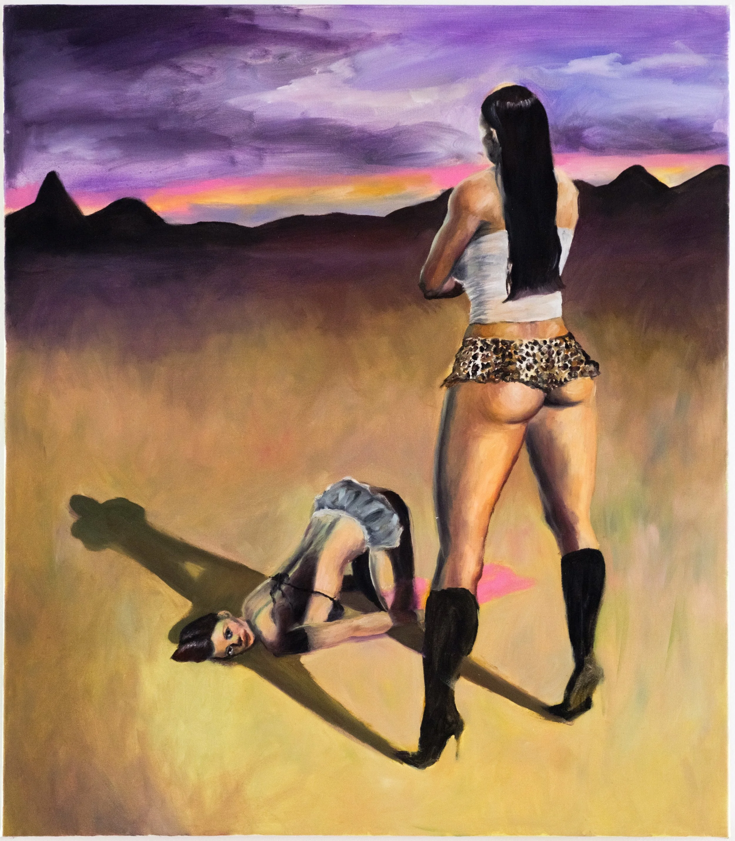 A woman with long dark hair, wearing a white tube top and animal-print shorts, is performing a handstand on a balance beam or similar bar structure. The background features a colorful sunset sky with dark mountains on the horizon.