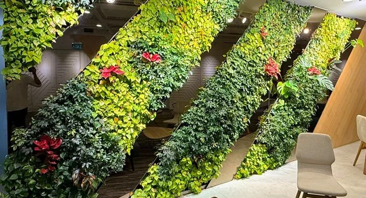 Interior space decorated with green vertical plant panels and pink flowers.