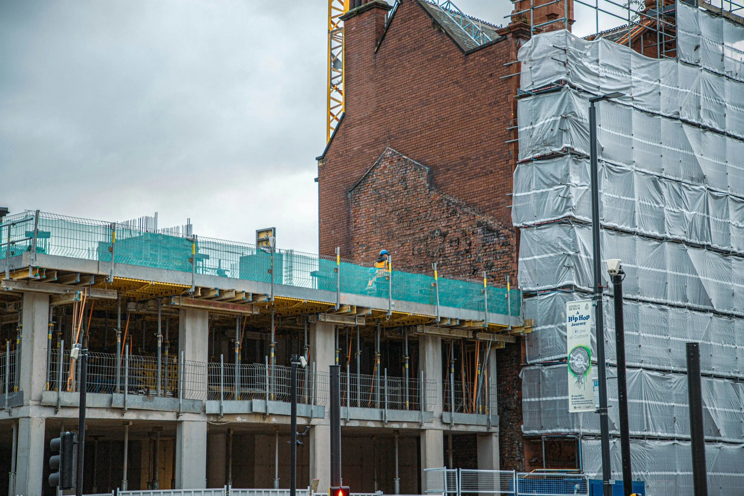 Construction worker on a commercial building development site with scaffolding and concrete structure, illustrating the type of new build projects requiring SBEM calculations