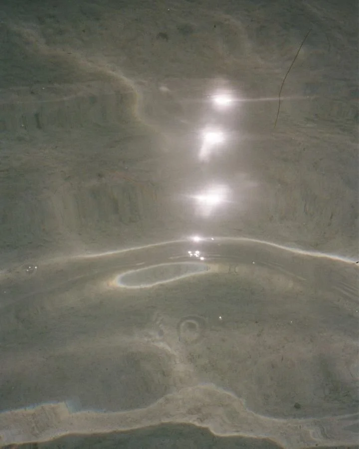 Close-up of a reflective surface, possibly marble or polished stone, showing highlights and natural textures.