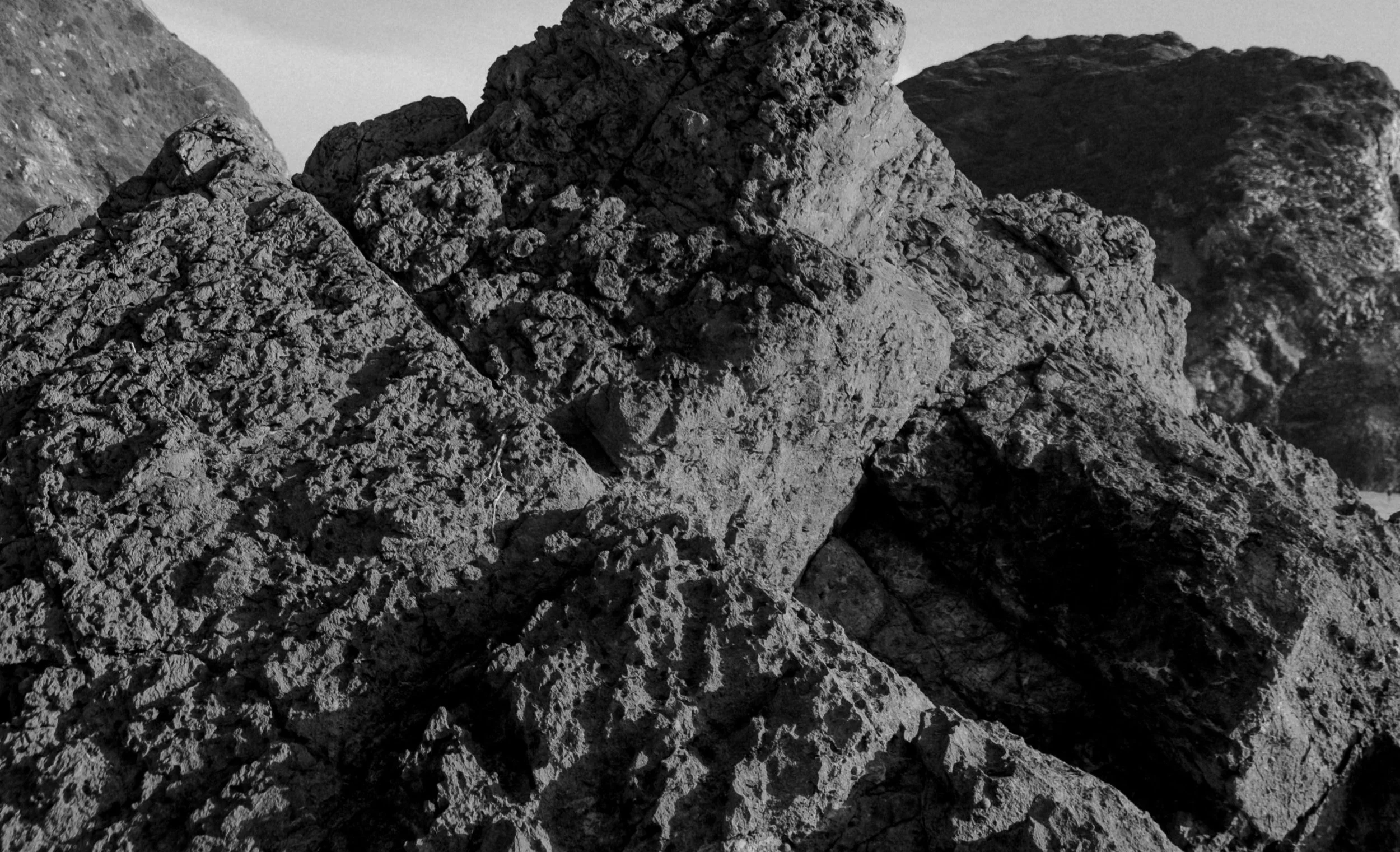 Black and white photograph of rough, textured rocks in an outdoor setting.