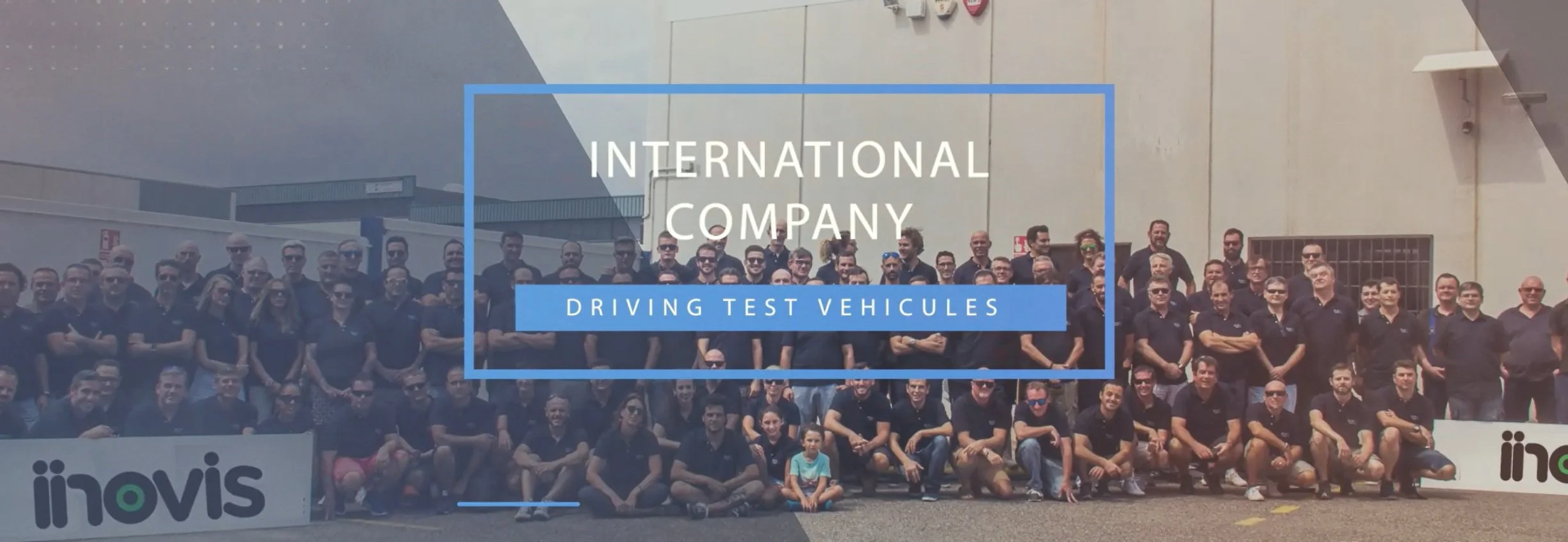 Group photo of people wearing black shirts with a sign reading 'Inovis' and a banner overlaid with text 'International Company Driving Test Vehicles.'