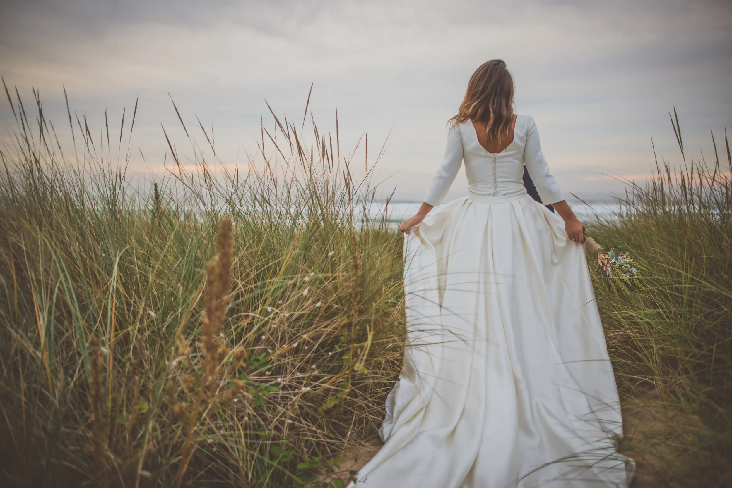 First kiss at a destination wedding overlooking the ocean in Spain by Lumen Atelier.