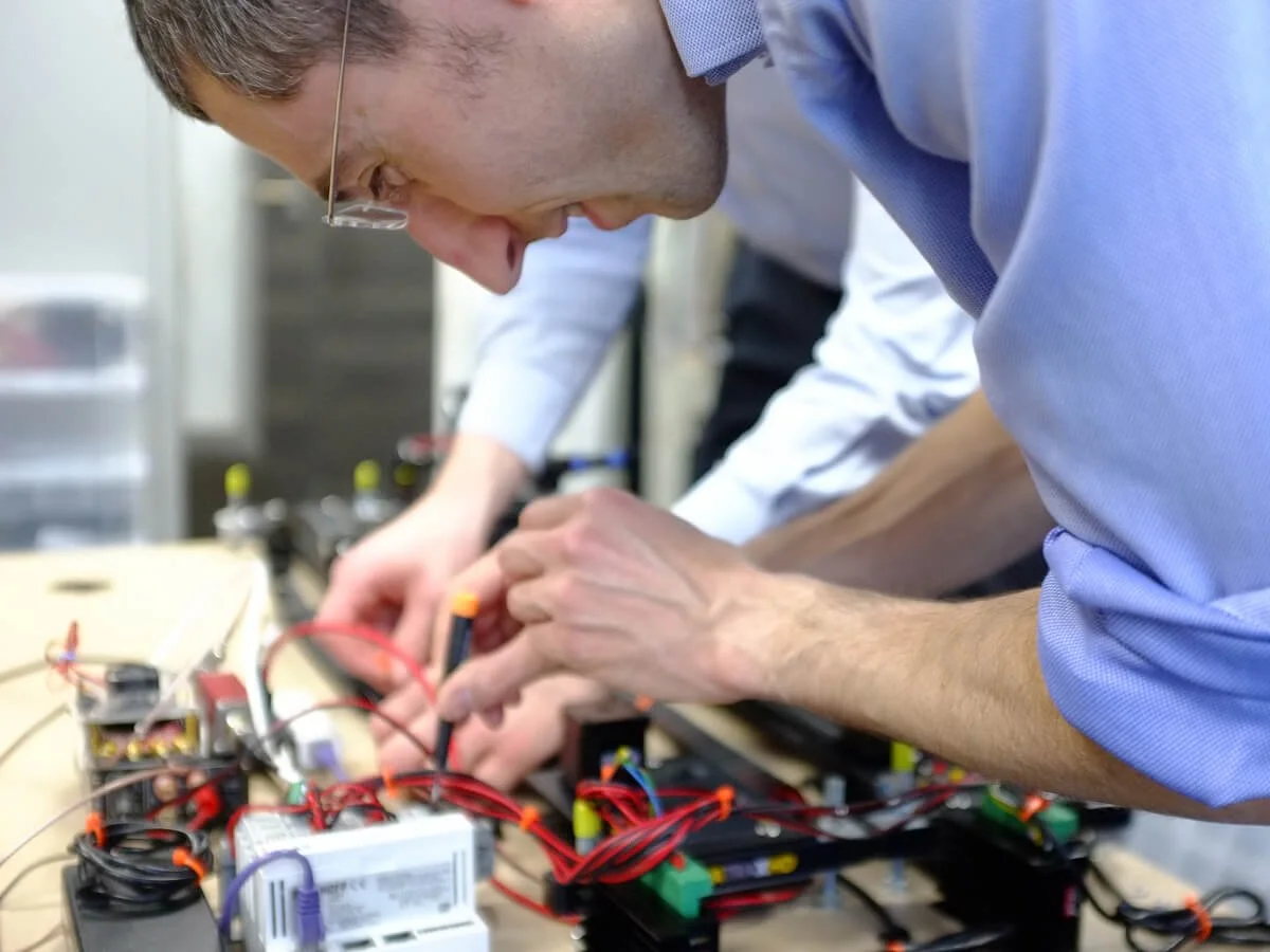 A man working on an electronics project with wires and circuit components on a table.