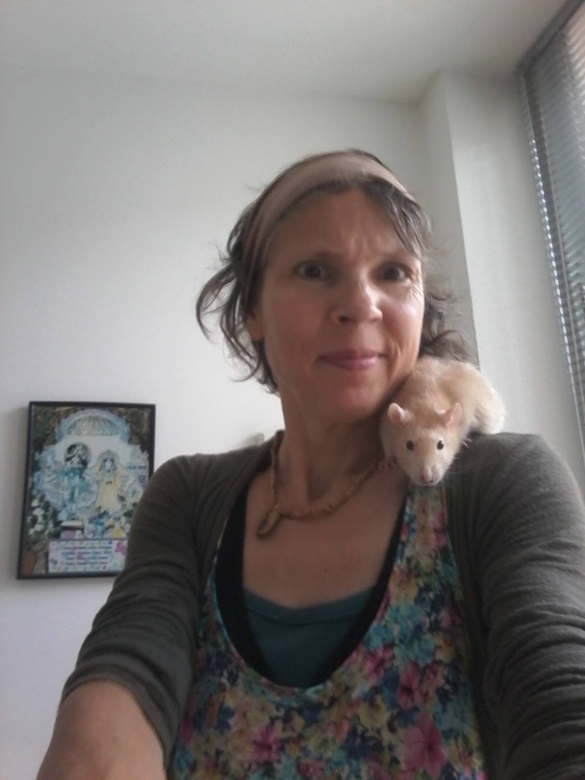 Petra Dungate smiling for a selfie with a cream-colored rat perched on her shoulder, reflecting the personal bond formed through animal communication work.