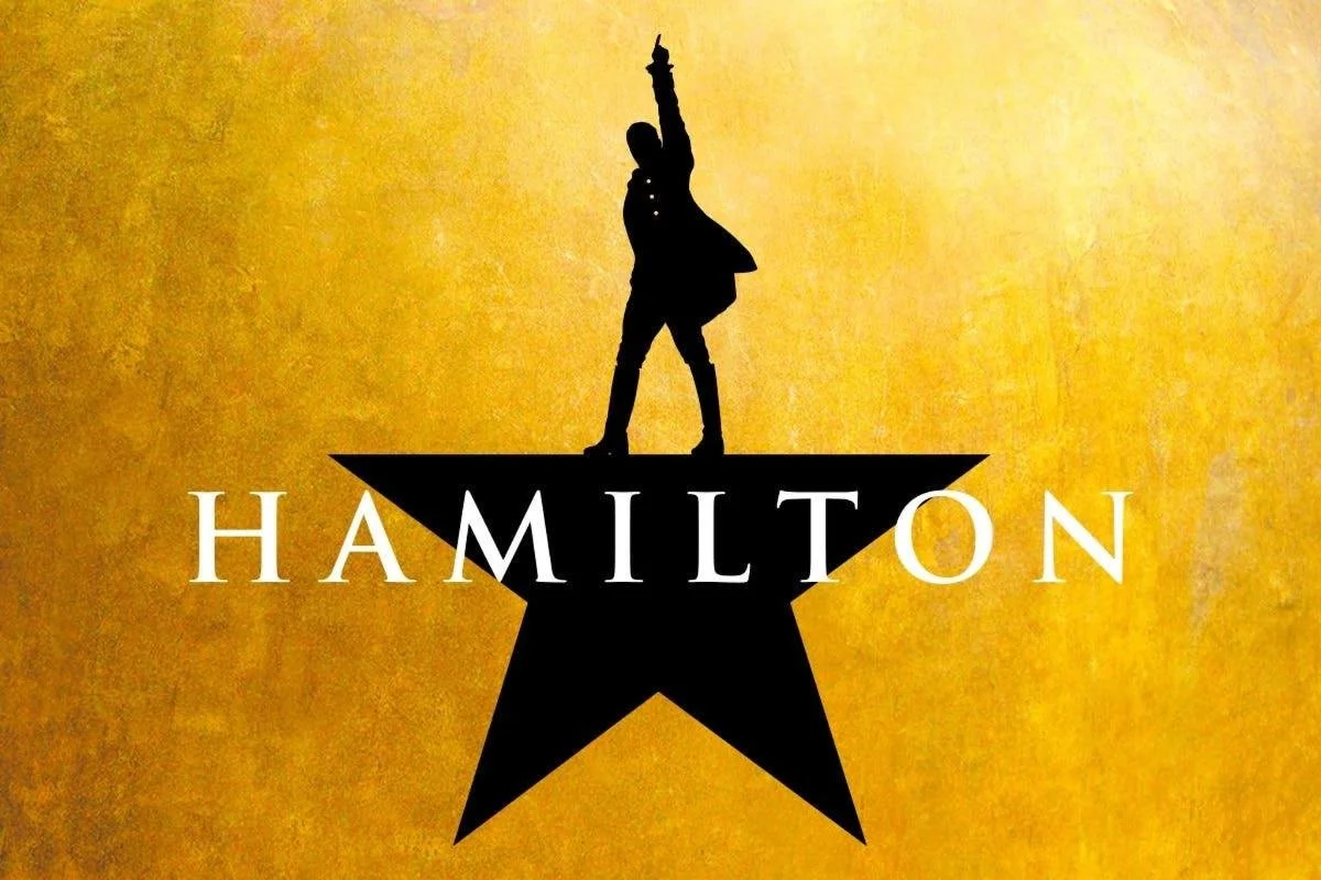 Silhouette of Alexander Hamilton standing on a star with one arm raised, set against a yellow textured background, with the word 'HAMILTON' written below.