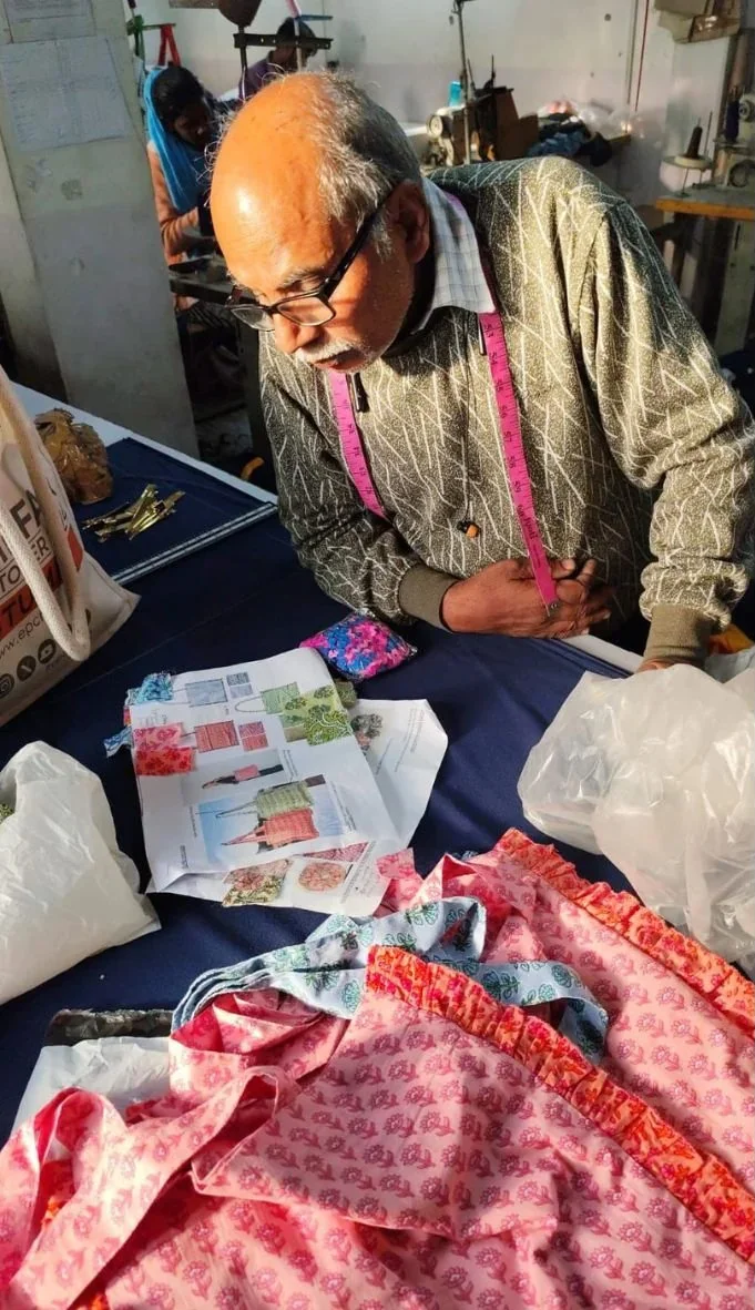 Man kijkt aandachtig naar stoffen en patronen op een tafel in een naaiatelier.