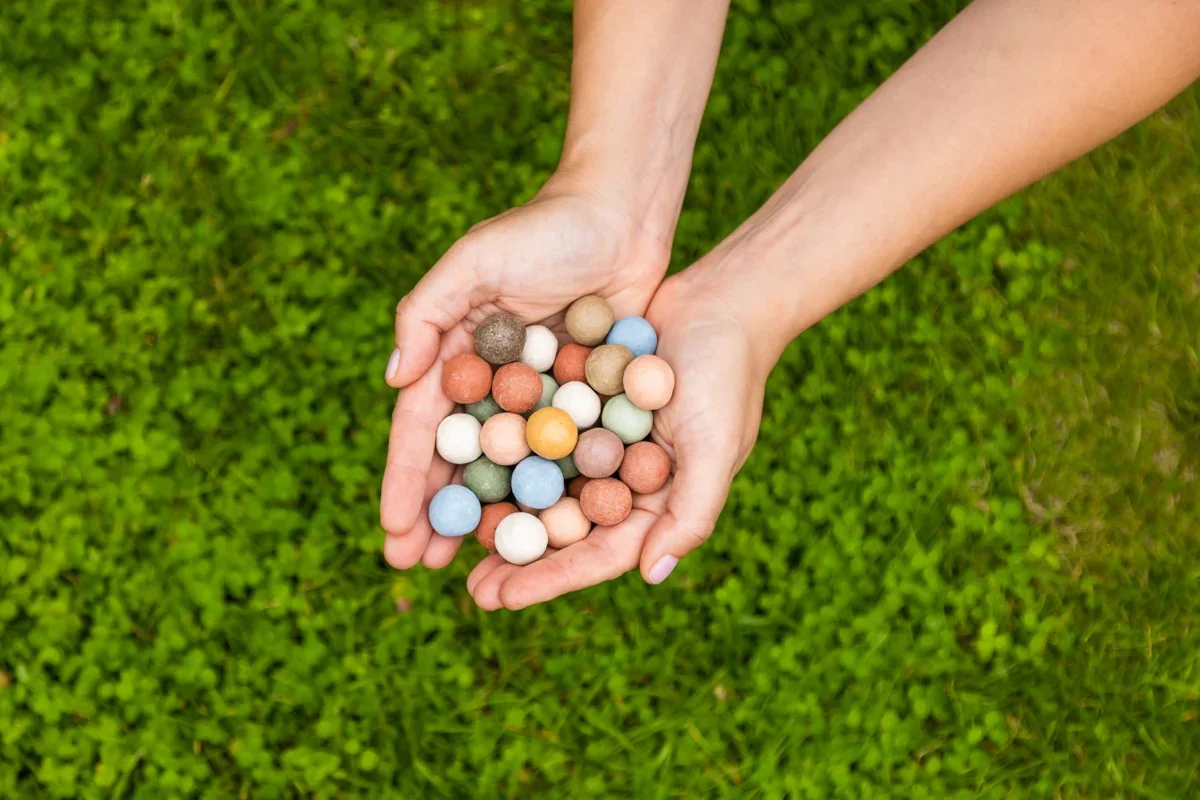 Twee handen houden een verzameling gekleurde karamellen boven gras
