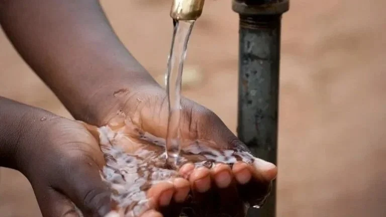 A person holding their hands under a running tap with water flowing over them.