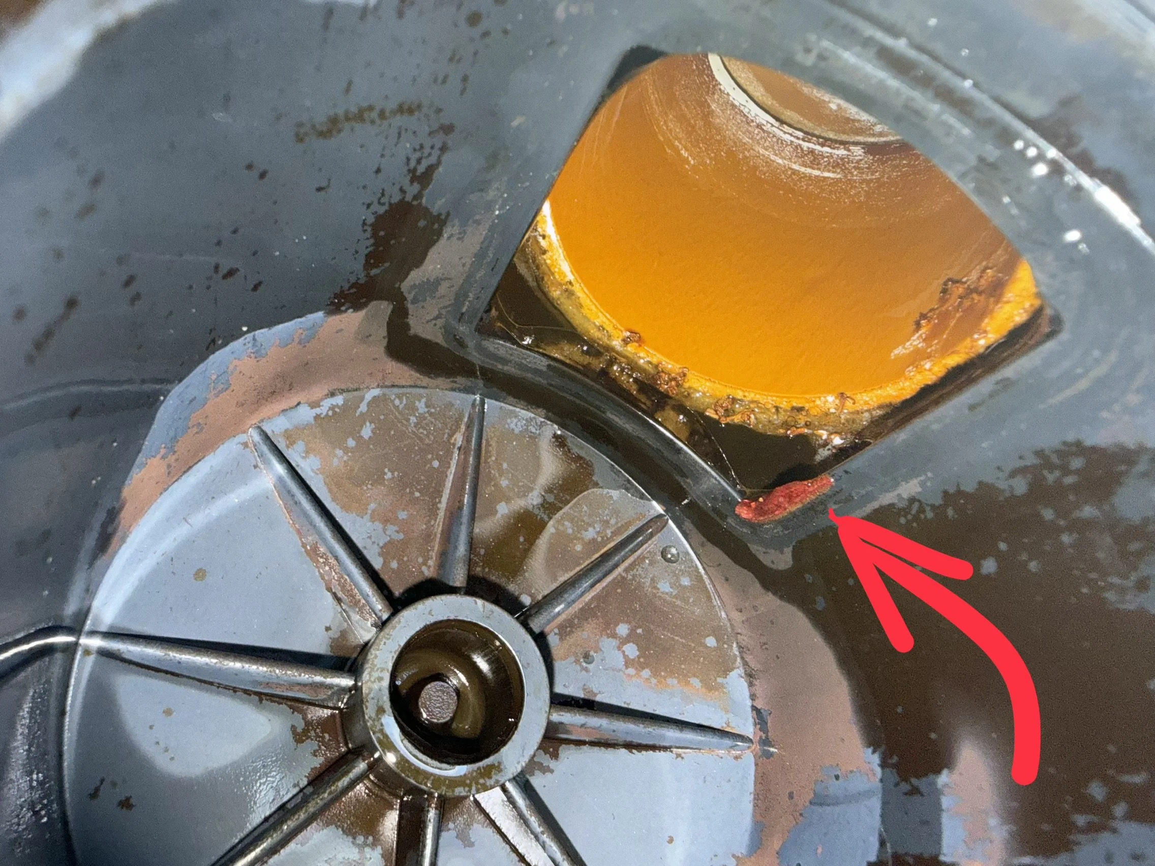 A stovetop with burned food and grease around the burners, and a red arrow pointing to a specific area.