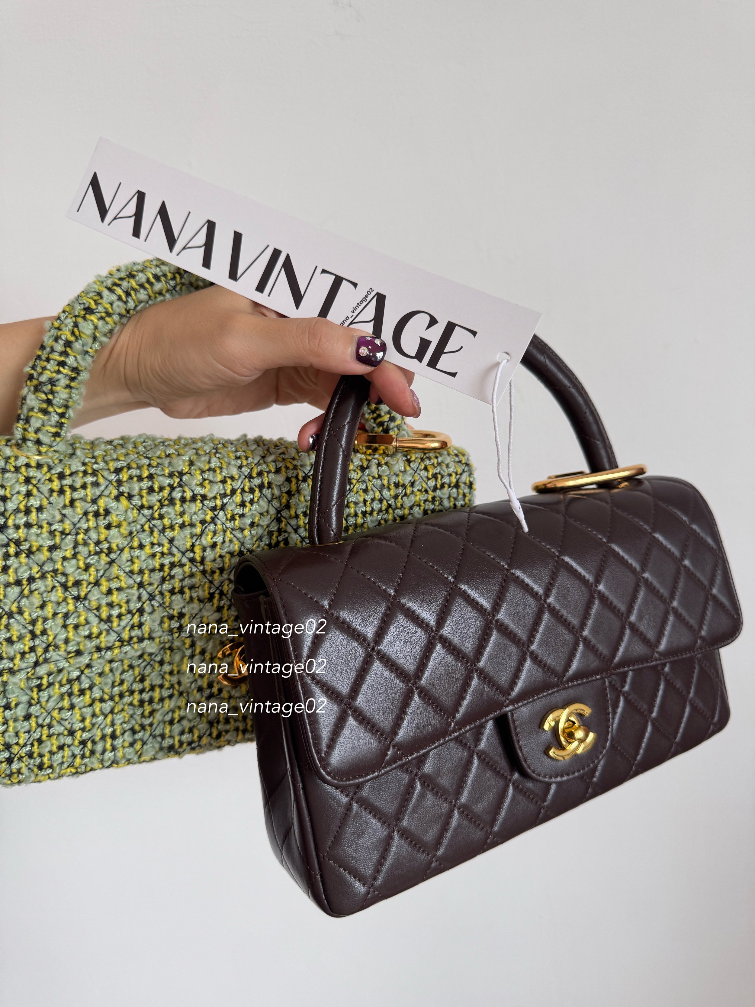 A hand holding a Nanavintage tag next to a rare Chanel vintage archive collection featuring a dark brown quilted leather classic flap bag and a green tweed textured handbag.⁠