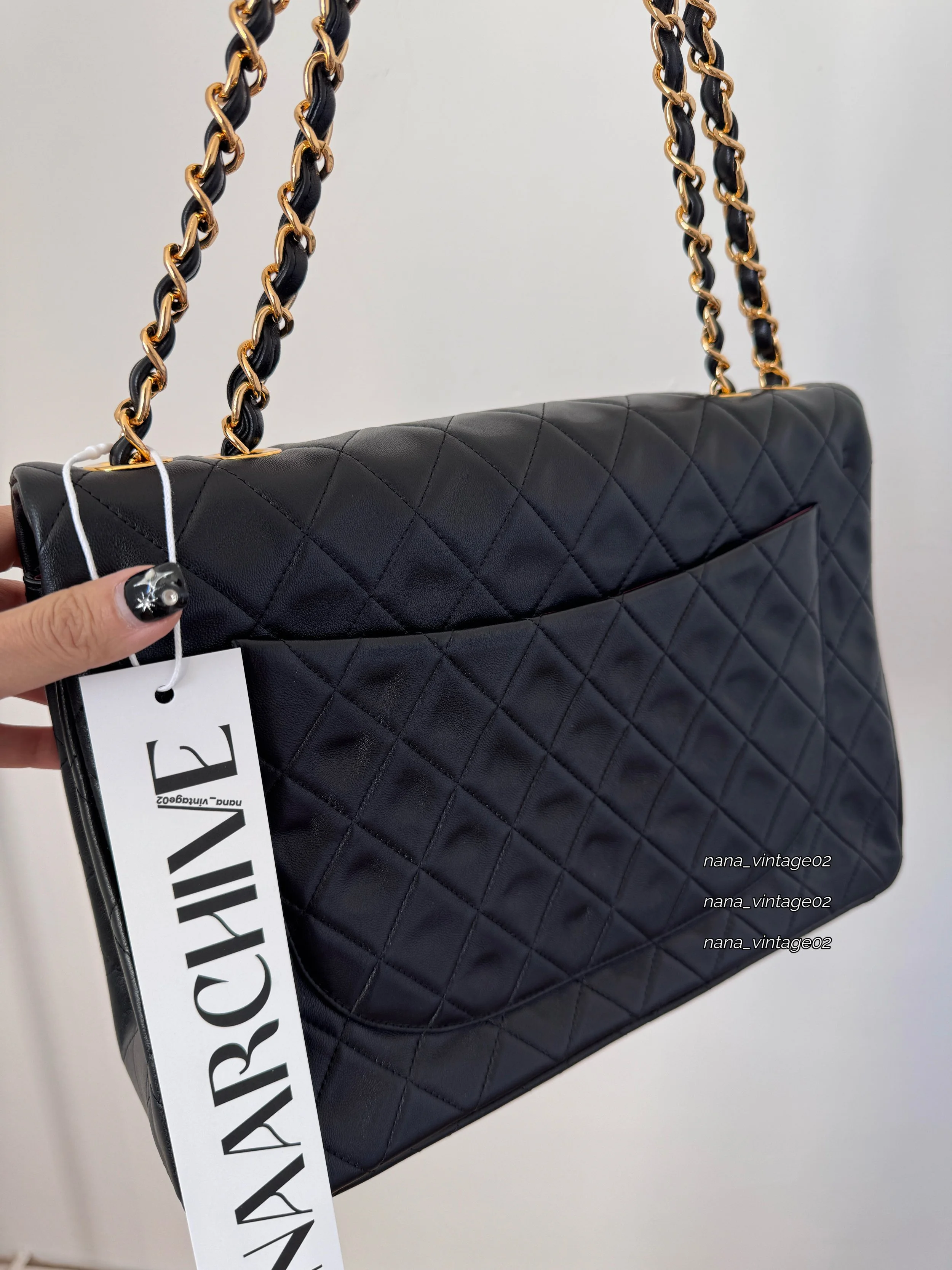 Detailed view of the back side of the handmade black quilted leather bag, showing the back pocket stitching, diamond pattern alignment, and gold chain hardware. 