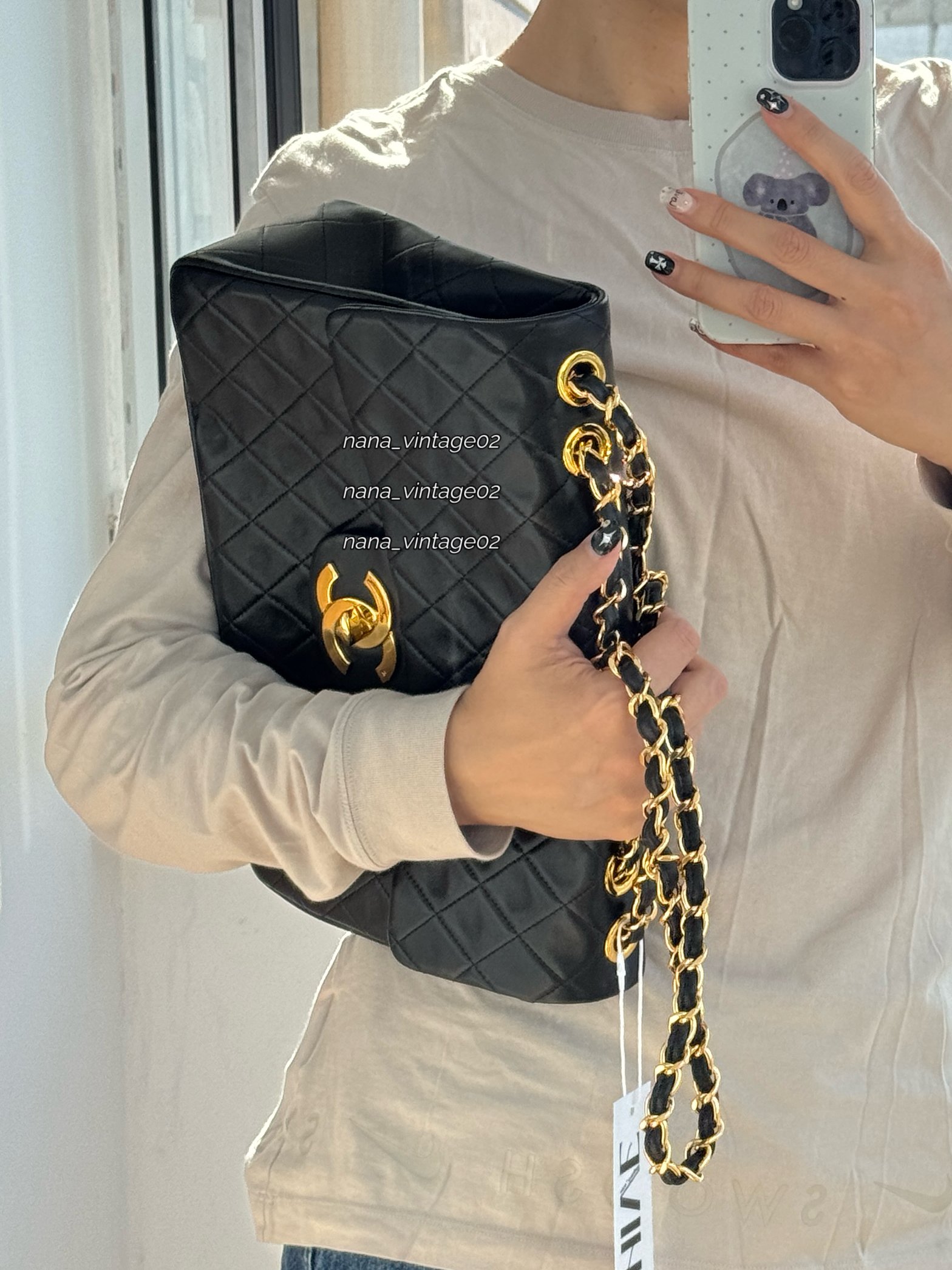 Side profile of a model holding the handcrafted black quilted flap bag, emphasizing its structure, leather texture, and draped chain strap.