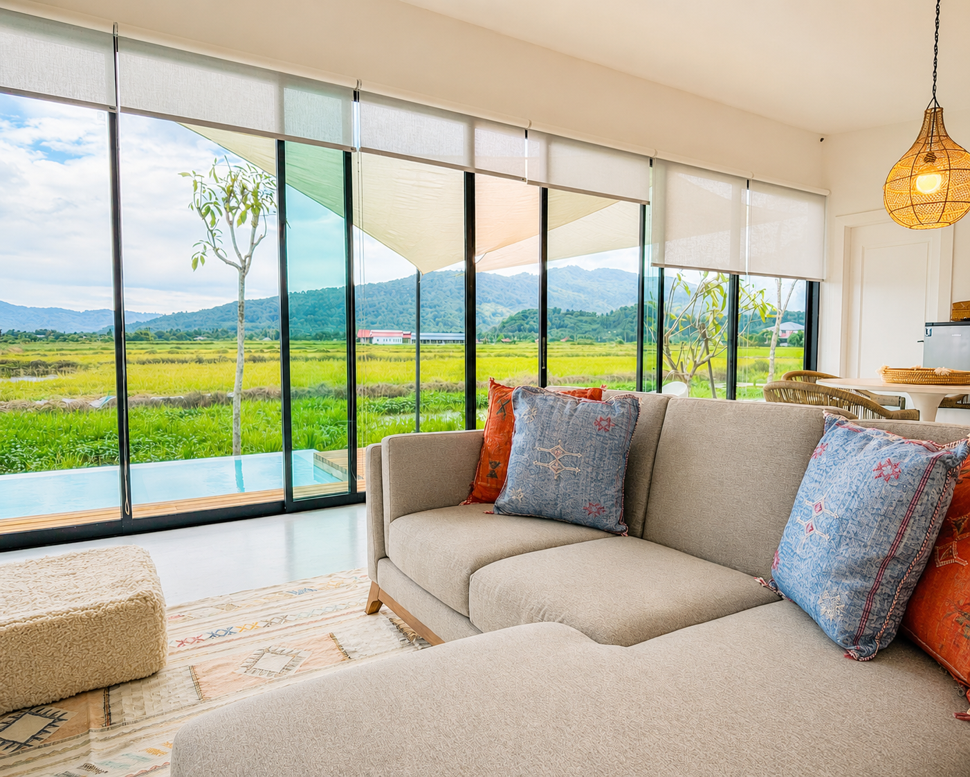 Living room sofa — floor-to-ceiling glass framing the green rice fields