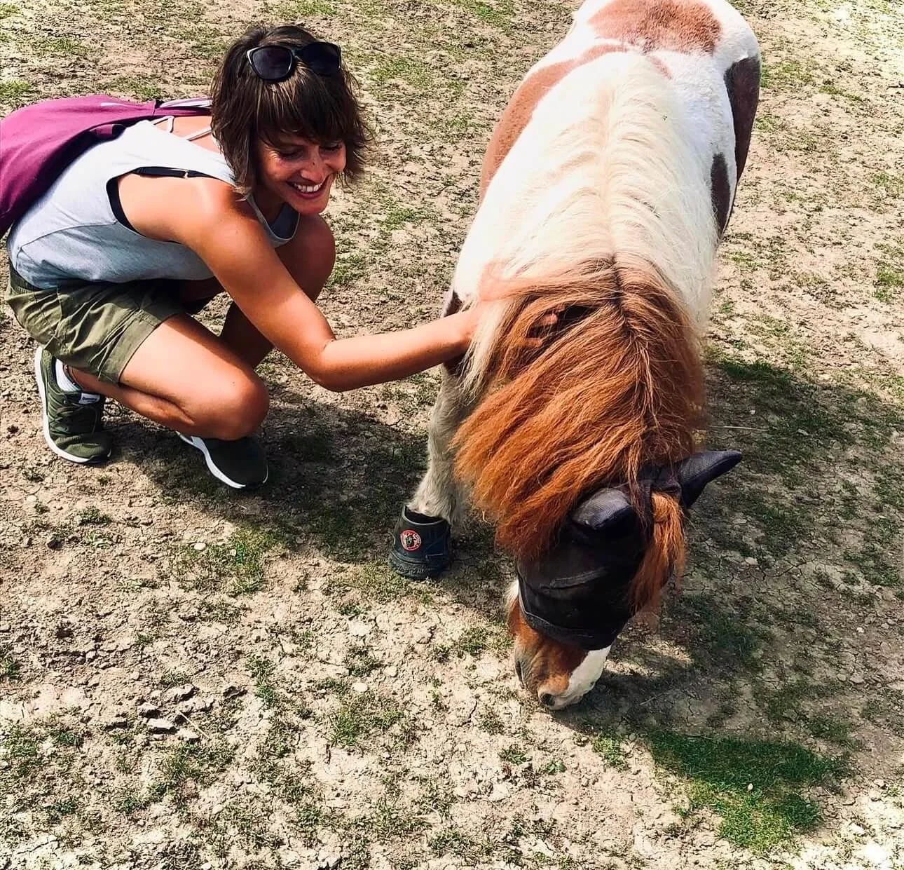 Vivian Vogel kniet auf einem Lebenhof und streichelt ein Pony