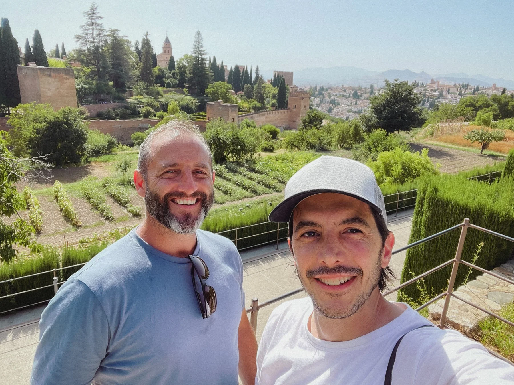 Fotógrafos de Buenafortuna sonriendo y tomando una selfie en Granada con jardines, muros y torres en el fondo, en un día soleado