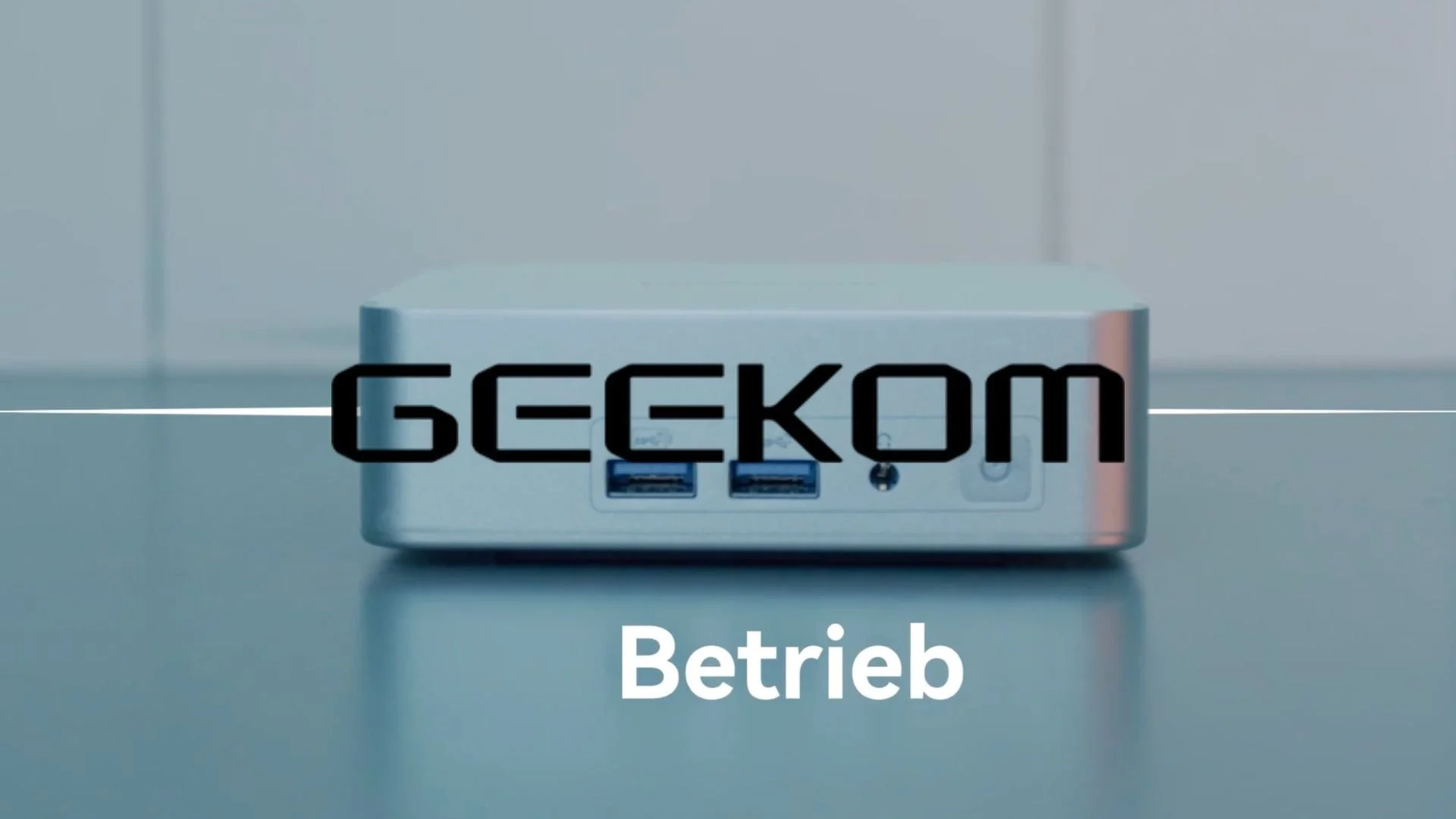 A close-up of a small electronic device with multiple ports, with the text 'GEEKOM' overlayed.
