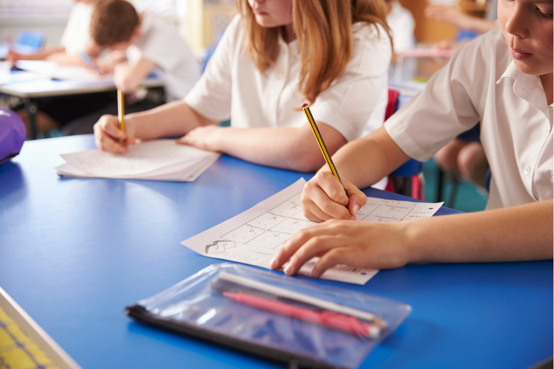 Students in a classroom working on worksheets at their desks.