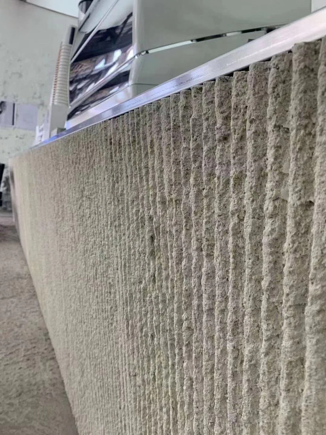 Close-up of a textured beige stone or concrete wall panel.