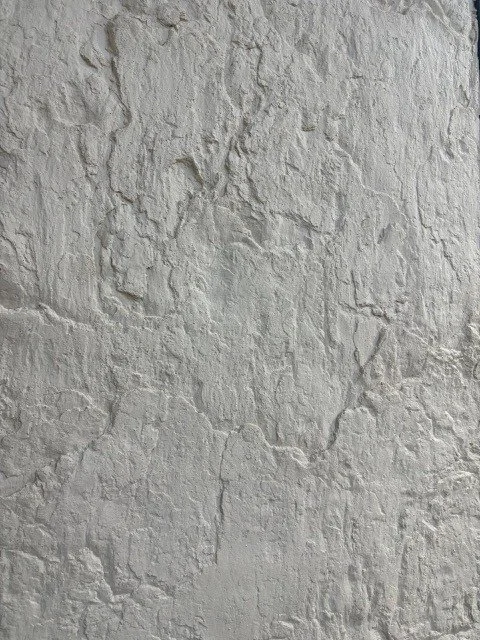 Close-up of a textured white wall with uneven surface and cracks.