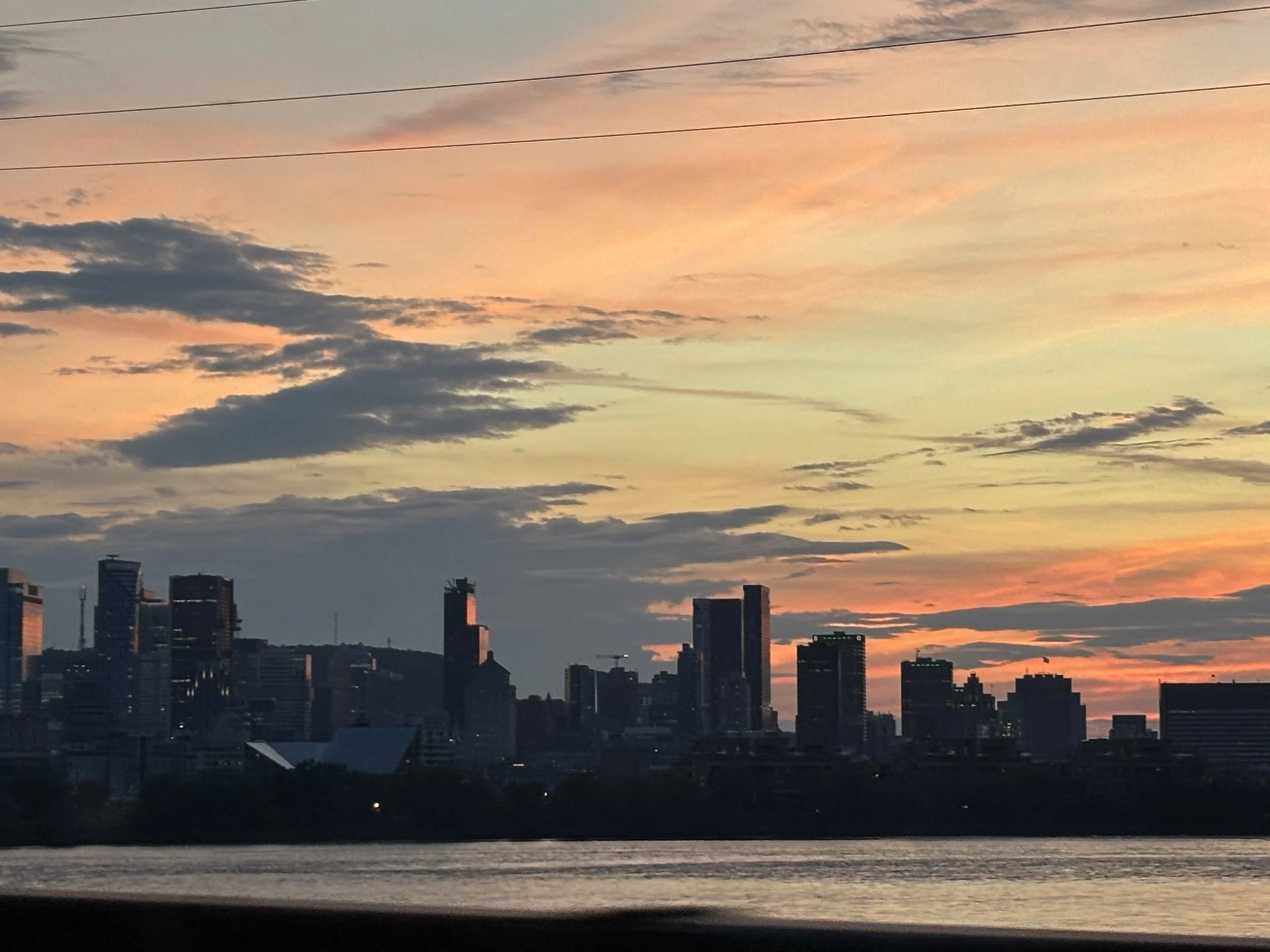 City skyline at sunset with colorful clouds and silhouetted buildings.