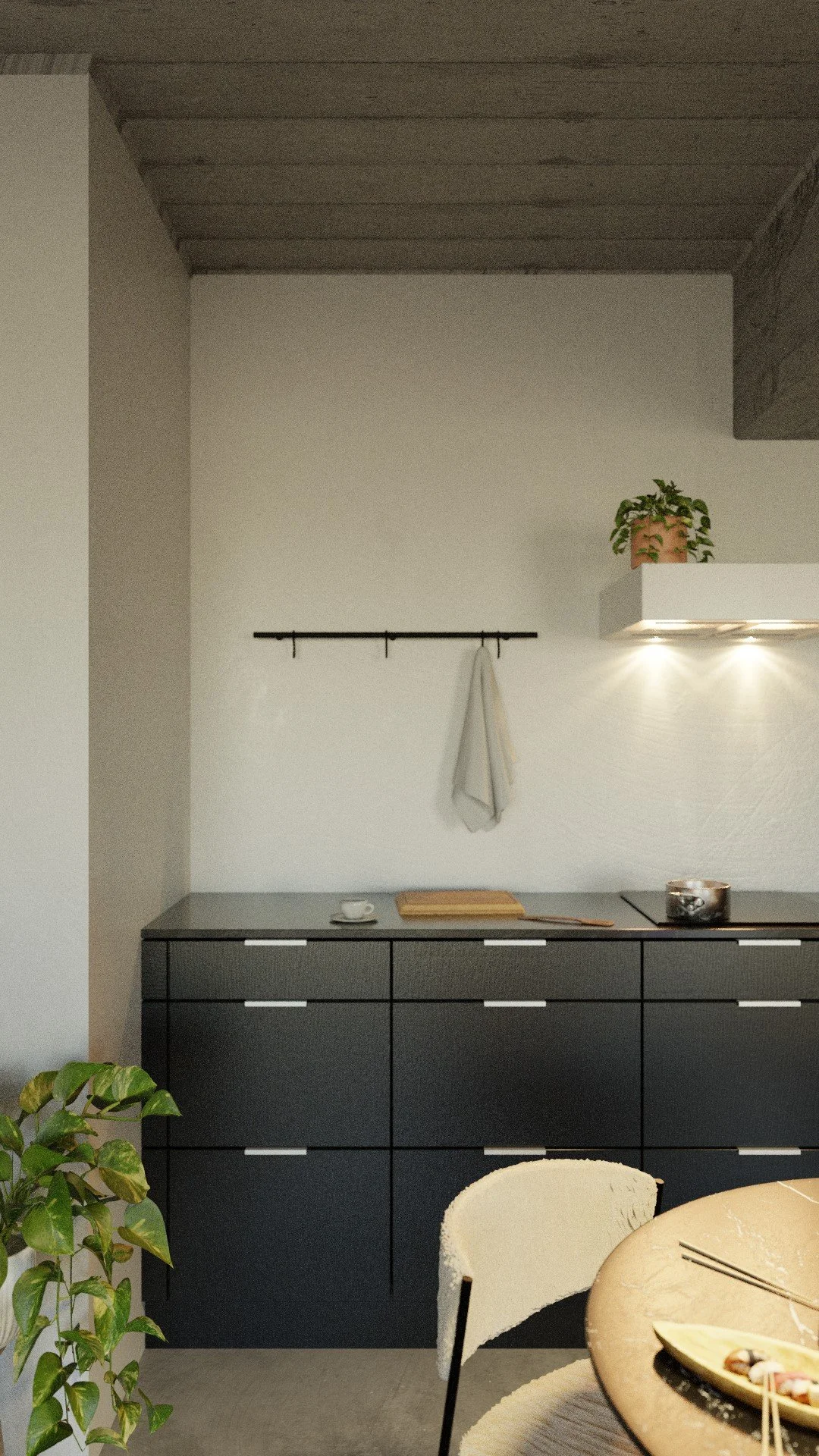 Modern kitchen with black cabinetry, a white wall with a black rod and hanging towel, a potted plant on a white shelf with under-cabinet lighting, a round dining table with a beige textured chair, and a plant in the bottom left corner.