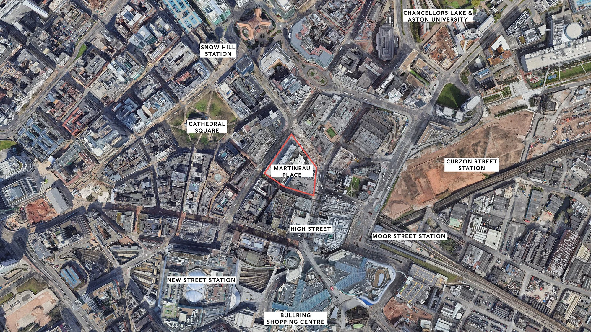 An aerial view of a city with roads, buildings, and parks. The image features labeled locations such as Snow Hill Station, Cathedral Square, Martineau Place, Chancellors Lake & Aston University, Curzon Street Station, High Street, Moor Street Station, New Street Station, and Bullring Shopping Centre. A red outline highlights the Martineau Place area.