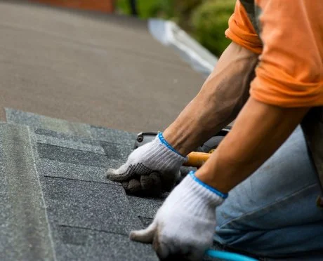 A person installing asphalt roofing.
