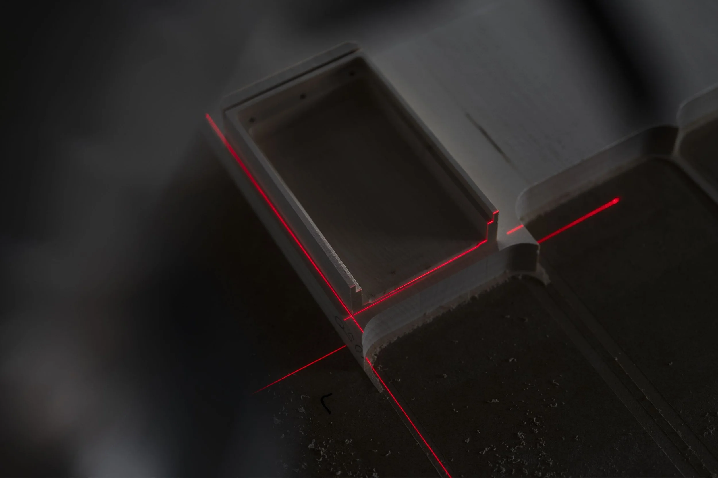 Close-up of a metallic object being precisely cut by a laser cutter, with red laser lines marking the cutting path.