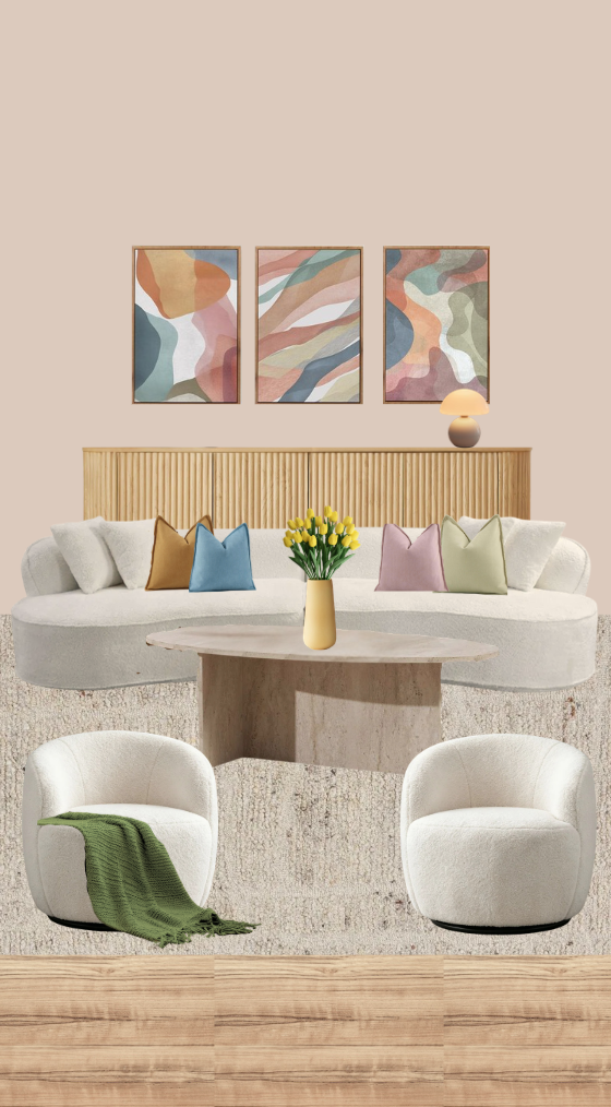 Modern living room with a white sofa, colorful throw pillows, a round coffee table with a yellow vase of yellow flowers, two white armchairs, one with a green blanket, abstract artwork on the wall, a wooden sideboard with a lamp, and a beige rug on a wooden floor.