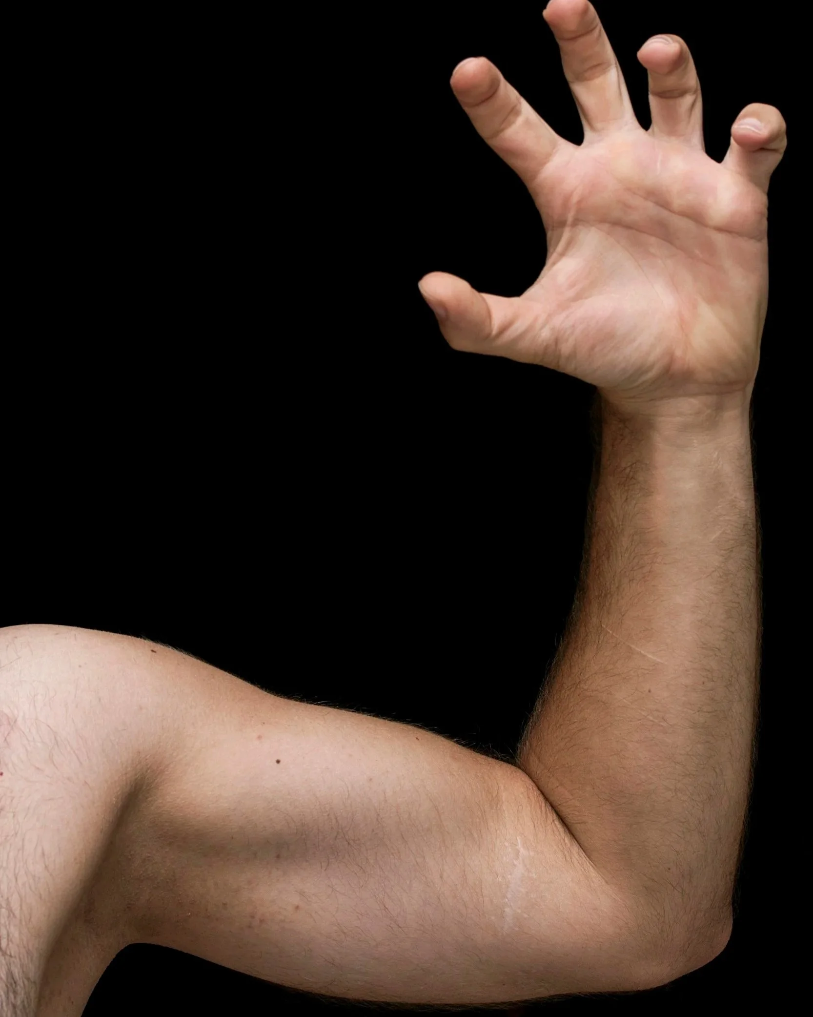 Close-up of a person's hand and arm resting on a bare chest with visible skin and body hair, against a black background. Joints
