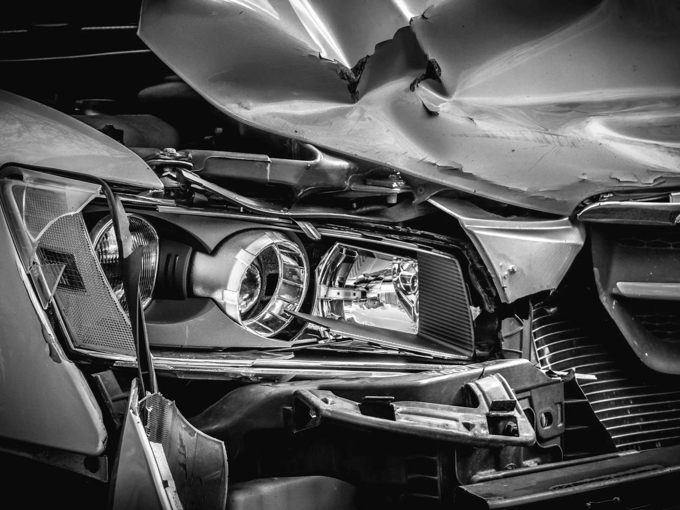 Black and white photo of a heavily damaged car with a crumpled front end and bent parts. Auto Accident treatment