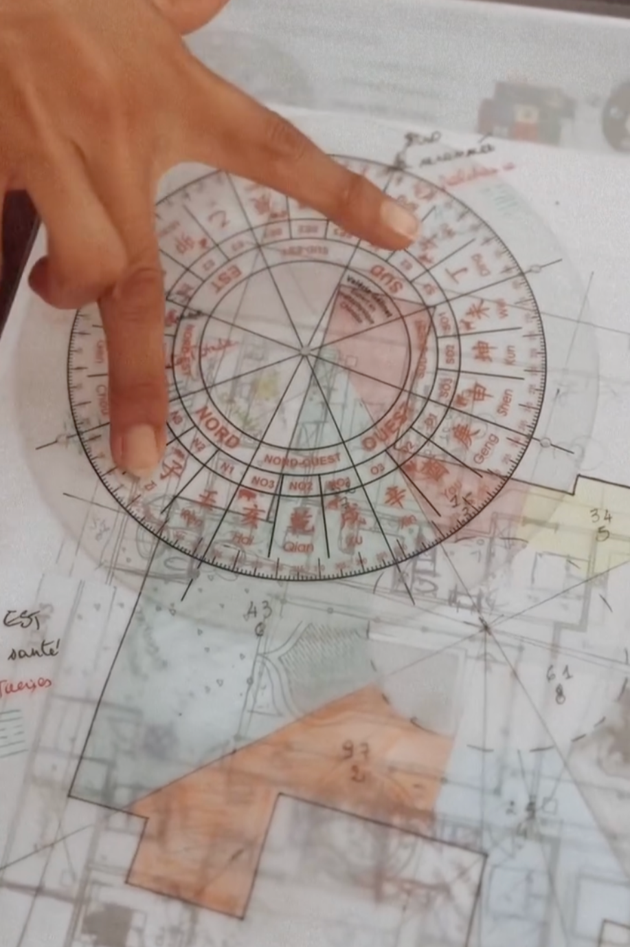 A person using a protractor and a ruler to mark measurements on a detailed architectural plan, with various handwritten notes and annotations.