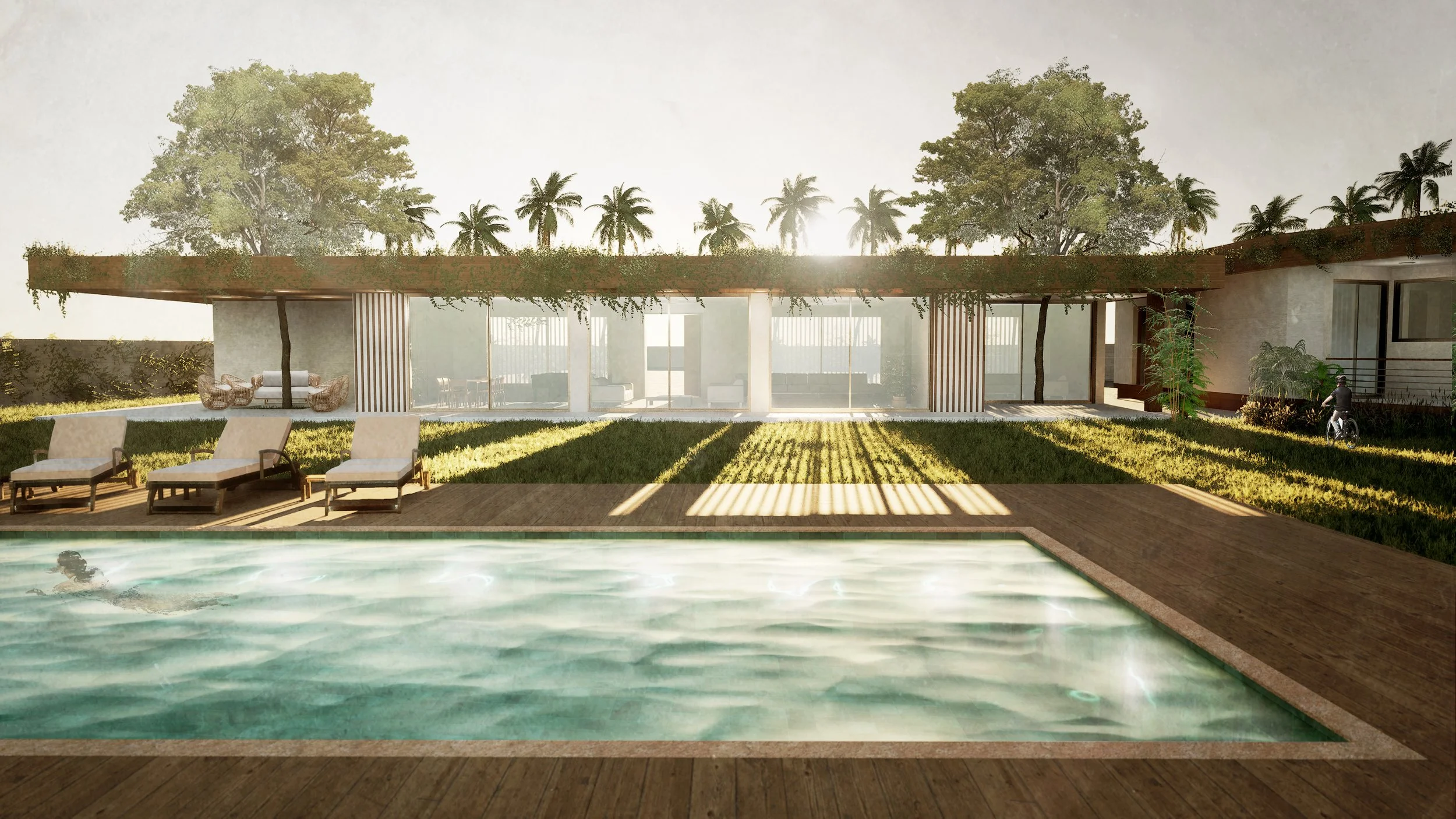 Modern house with large glass windows, outdoor pool, wooden deck, lounge chairs, lush green yard, trees, and a person riding a bicycle at sunset.