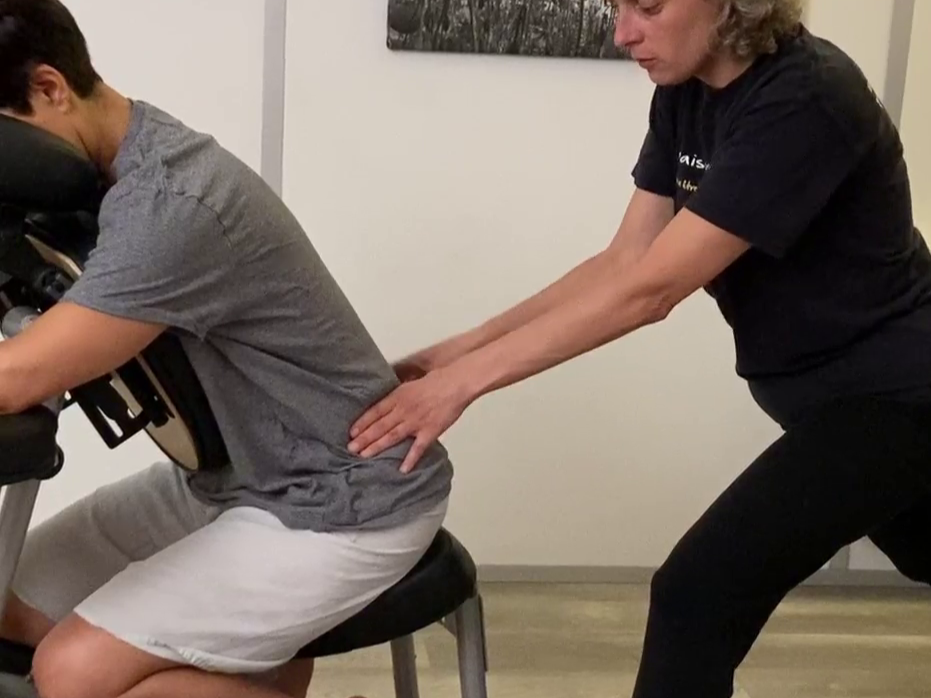 Un professionnel de la santé pratique une thérapie de la colonne vertébrale sur un patient assis sur une chaise dans une clinique.