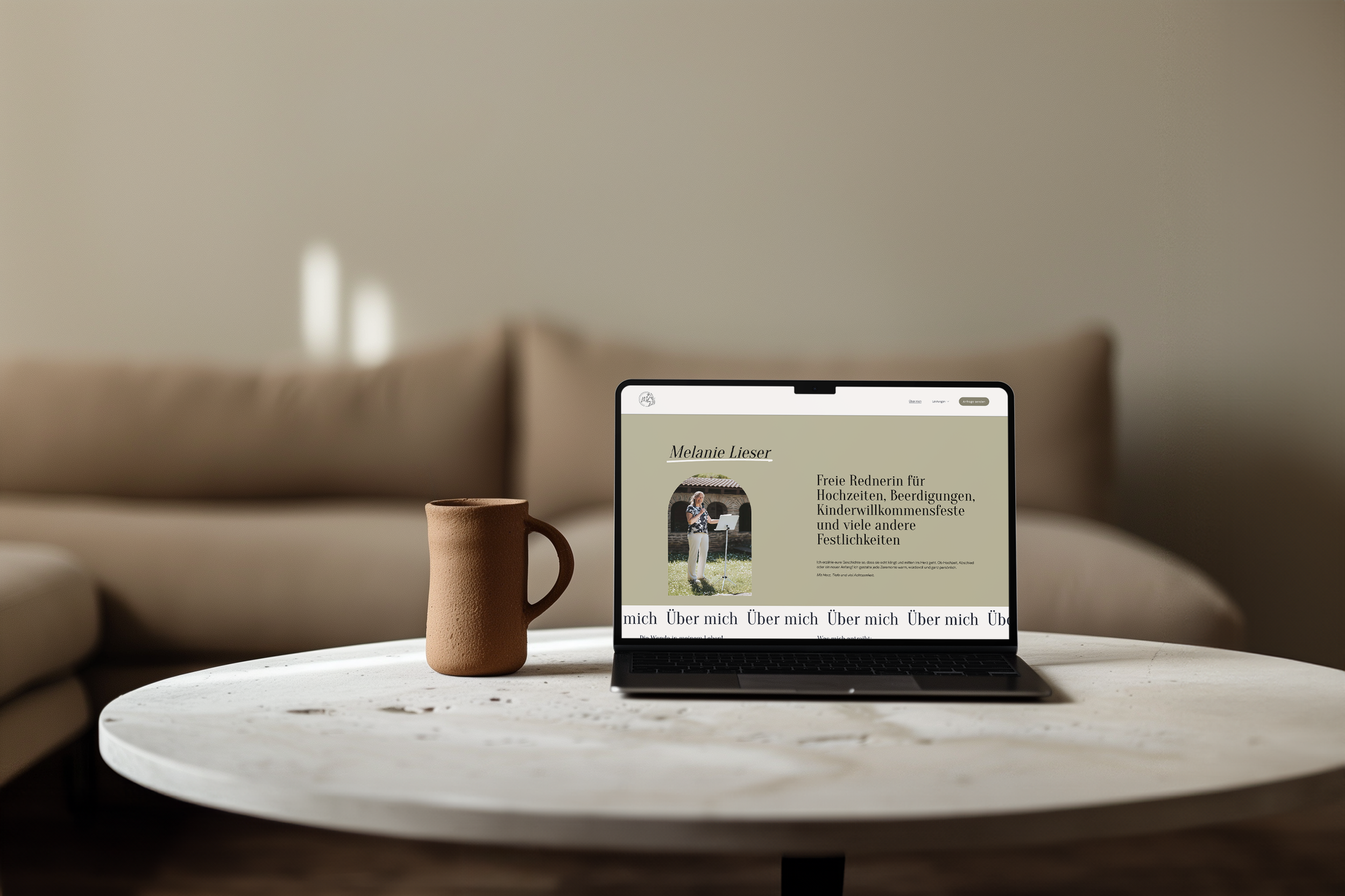 Ein Laptop auf einem weißen Terrassentisch zeigt eine Webseite der Rednerin Melanie Liser mit Bild und Text. Ein brauner Keramikkrug steht daneben. Im Hintergrund ein beige Couch und eine Wand.