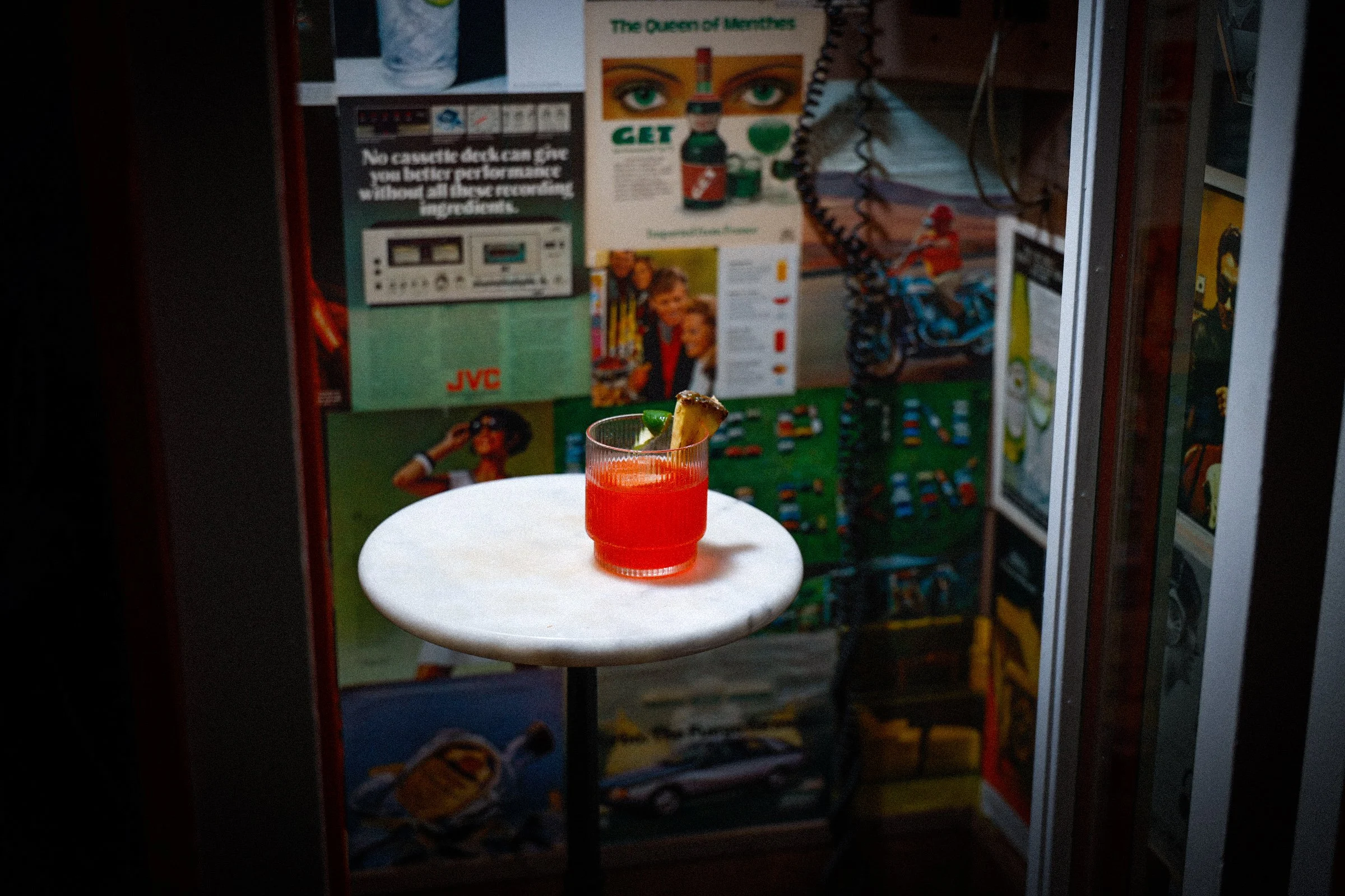 A cocktail sitting on a table in a vintage phone booth