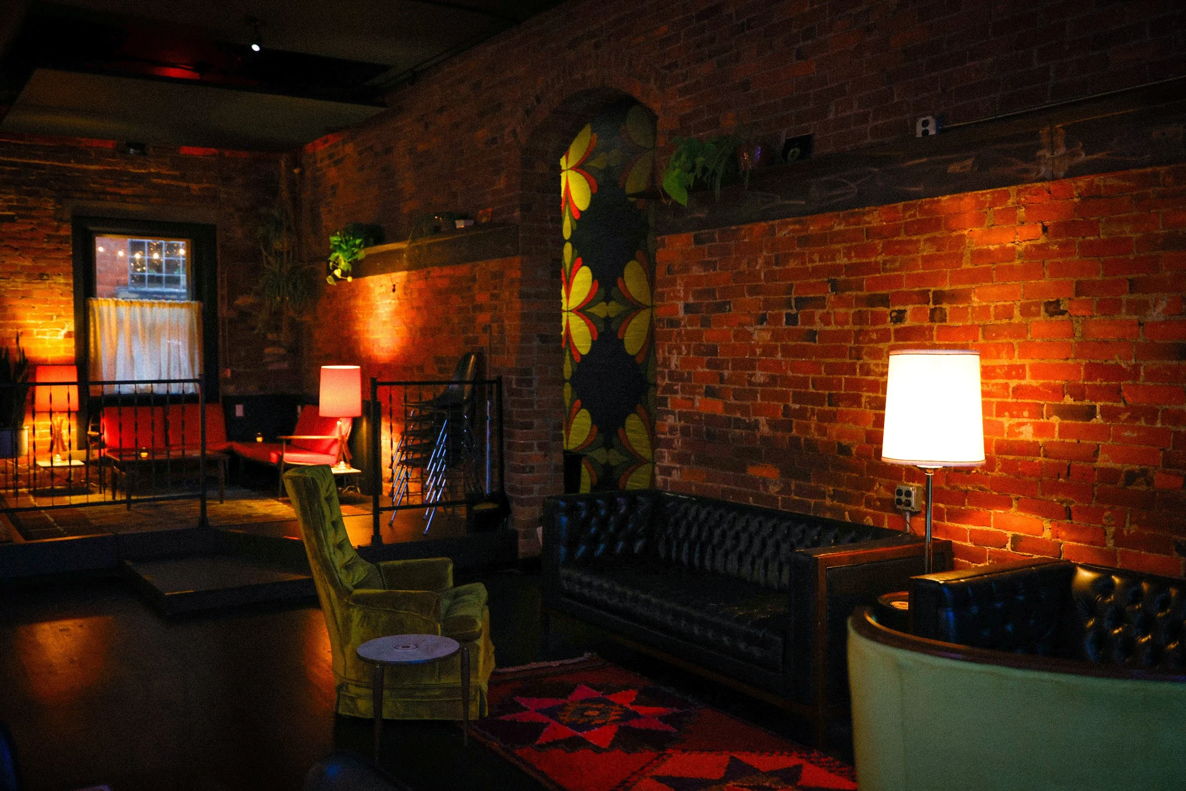 Dimly lit and cozy lounge area with vintage seating, rugs, and decor