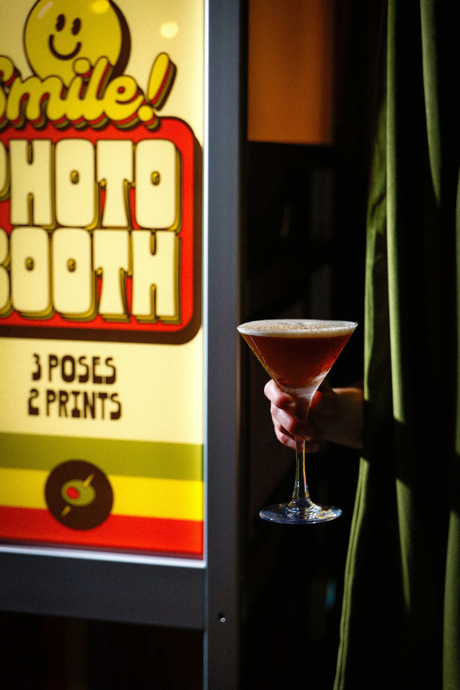 Hand holding espresso martini coming out of photo booth