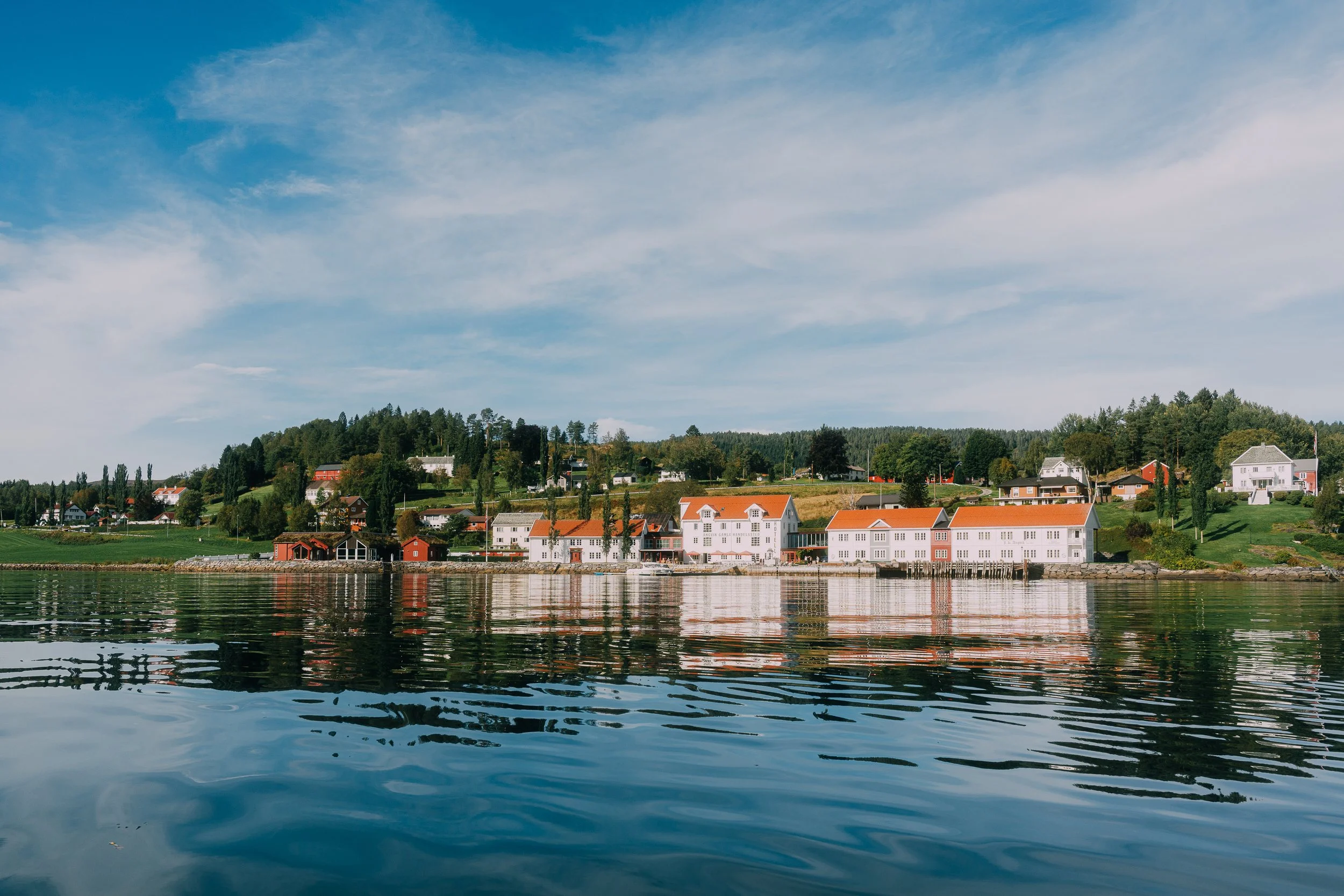 Skandinavisk kystlandsby speilet i stille vann