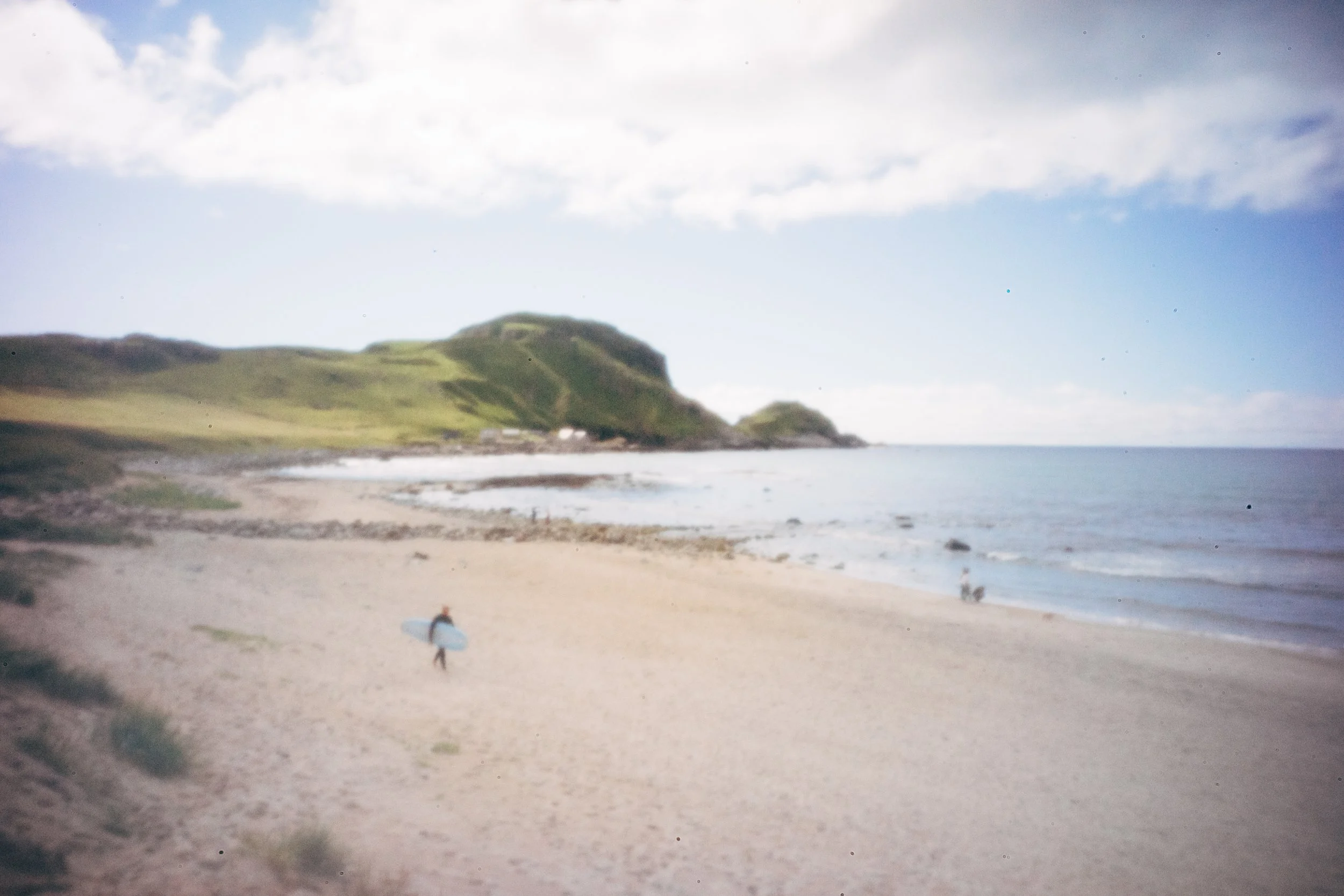 Øde sandstrand omgitt av dramatiske klipper og hav